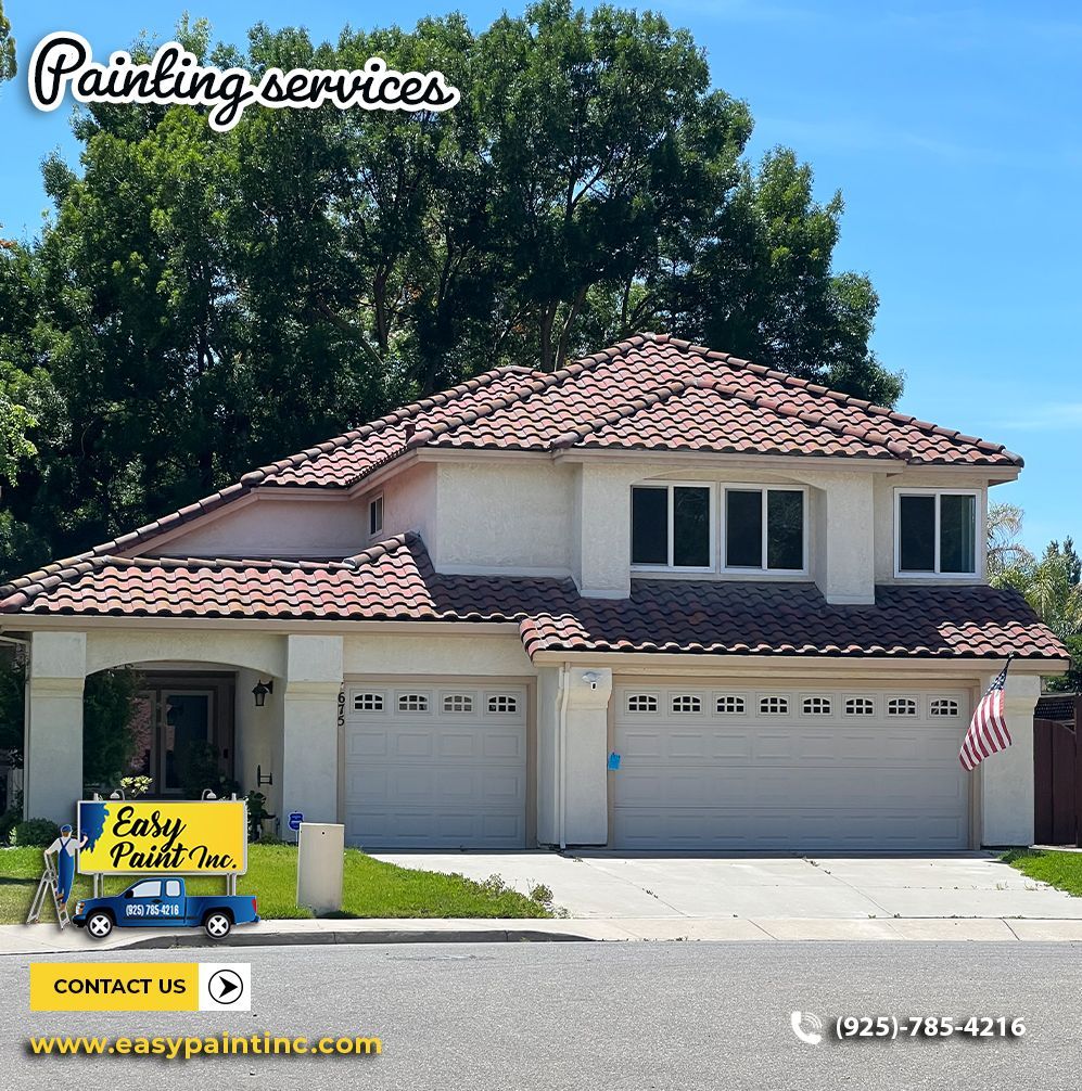 Two-story house with tan stucco exterior, tile roof, garage doors. Painting service logo on a truck.