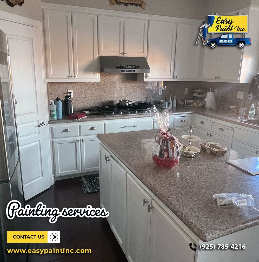 Kitchen cabinets painted white. Island with countertop, stovetop, and granite backsplash. Painting service ad in the corner.