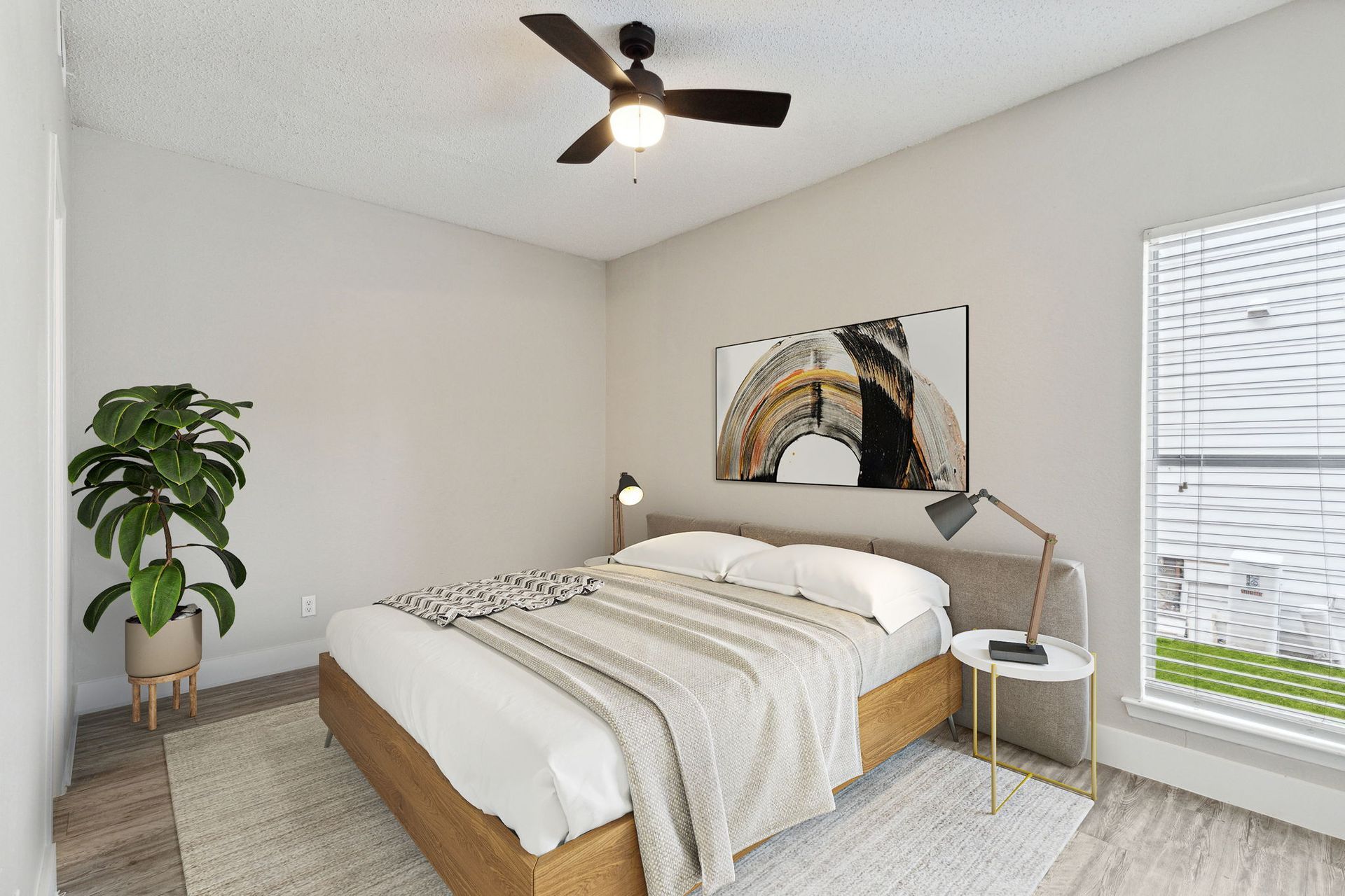 Bedroom with a bed, plant, art, a rug, and a window. The walls are light.