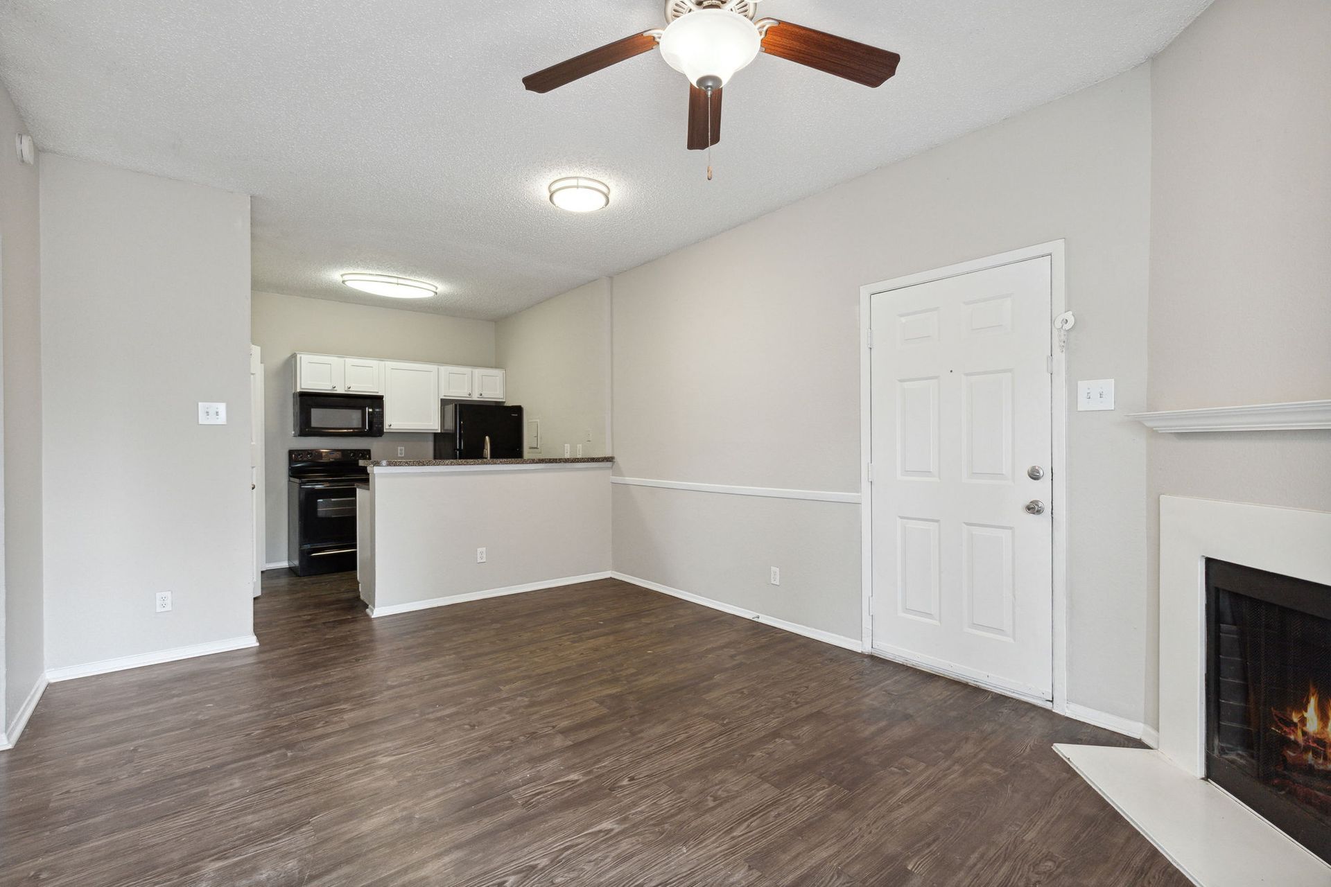 Living room with a fireplace, a kitchen, and grey flooring.