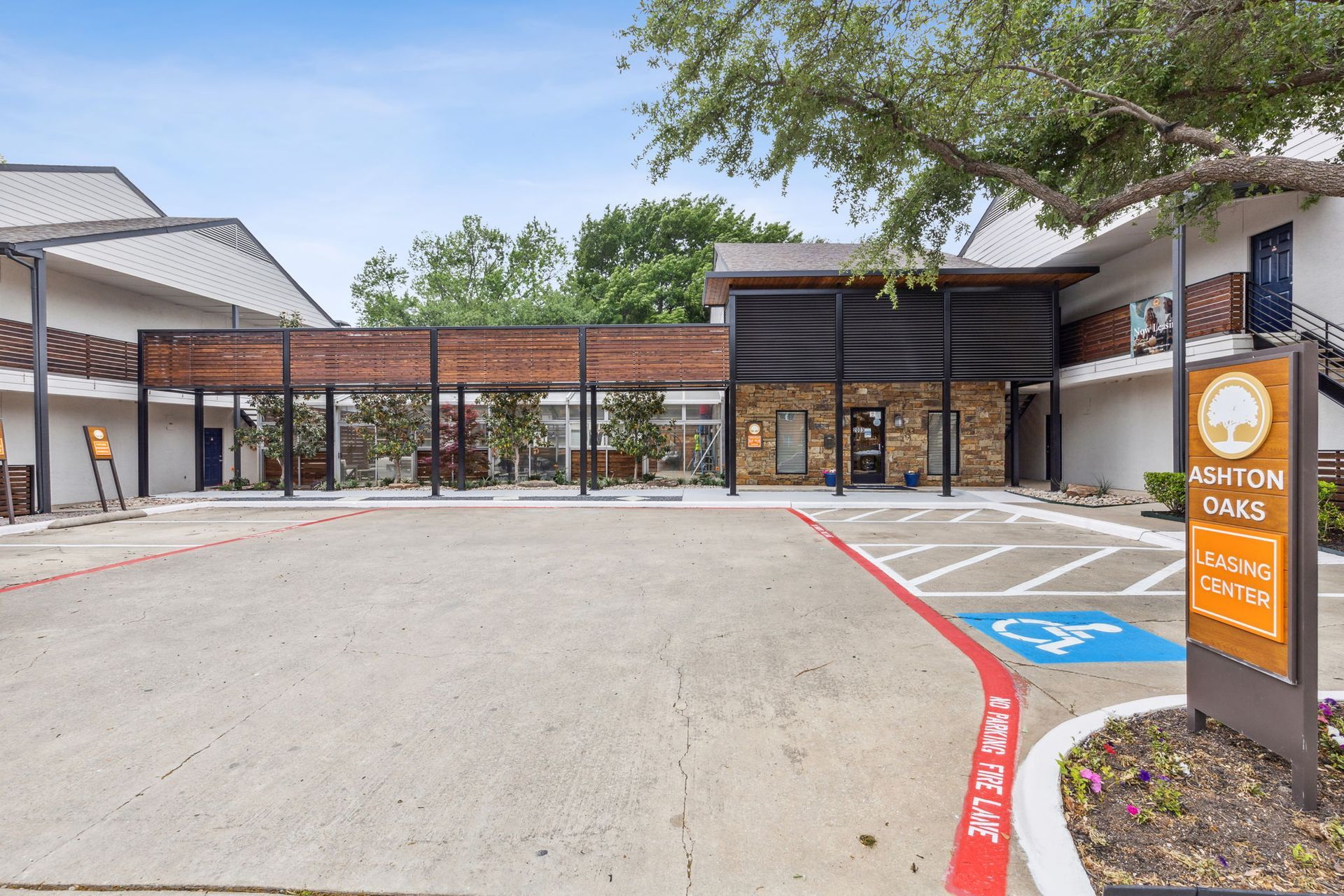 Exterior of Avalon Oaks apartments, with a parking lot, sign, and building with accessibility parking.