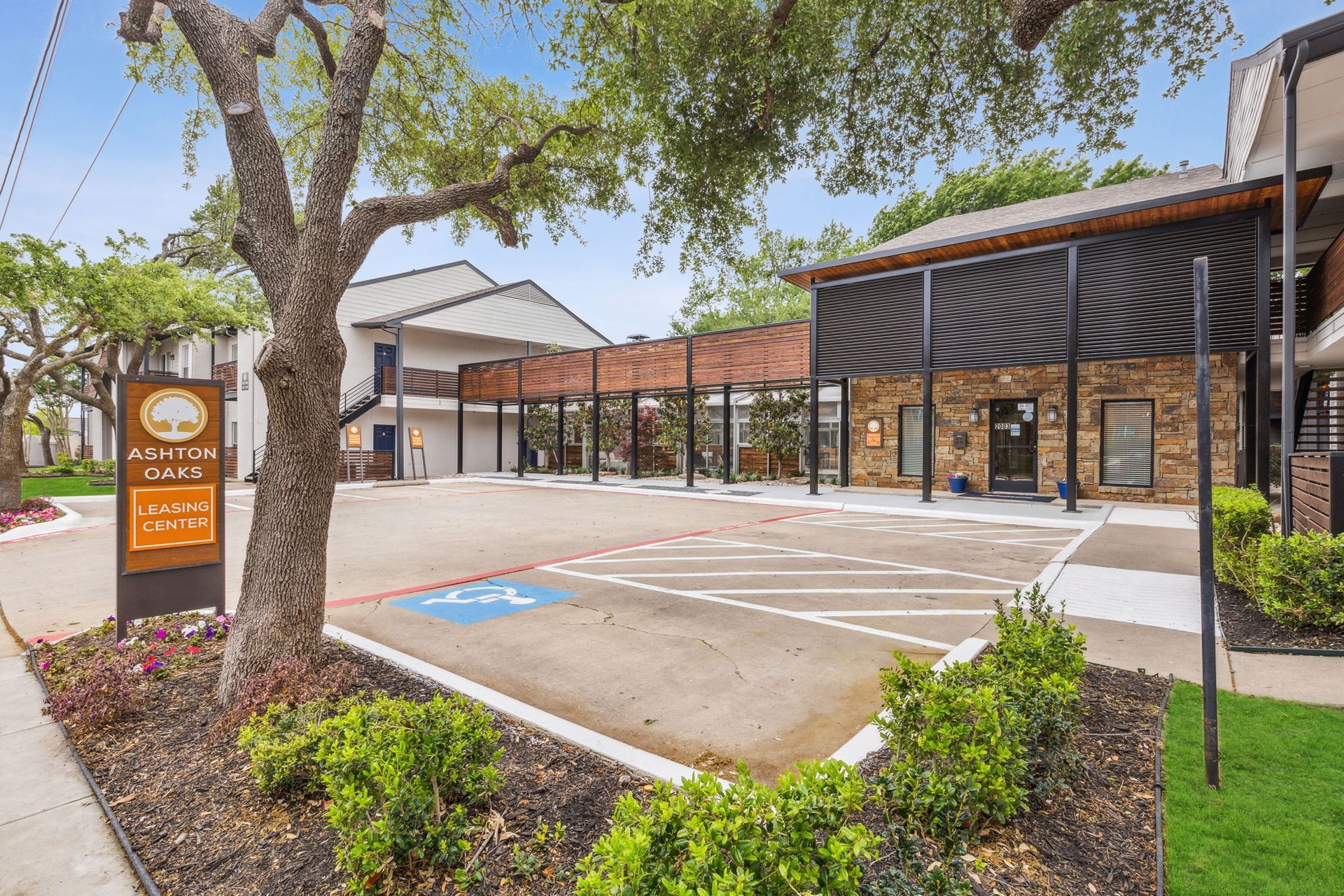 Exterior of a building with a parking lot, featuring a handicap parking spot and a sign.