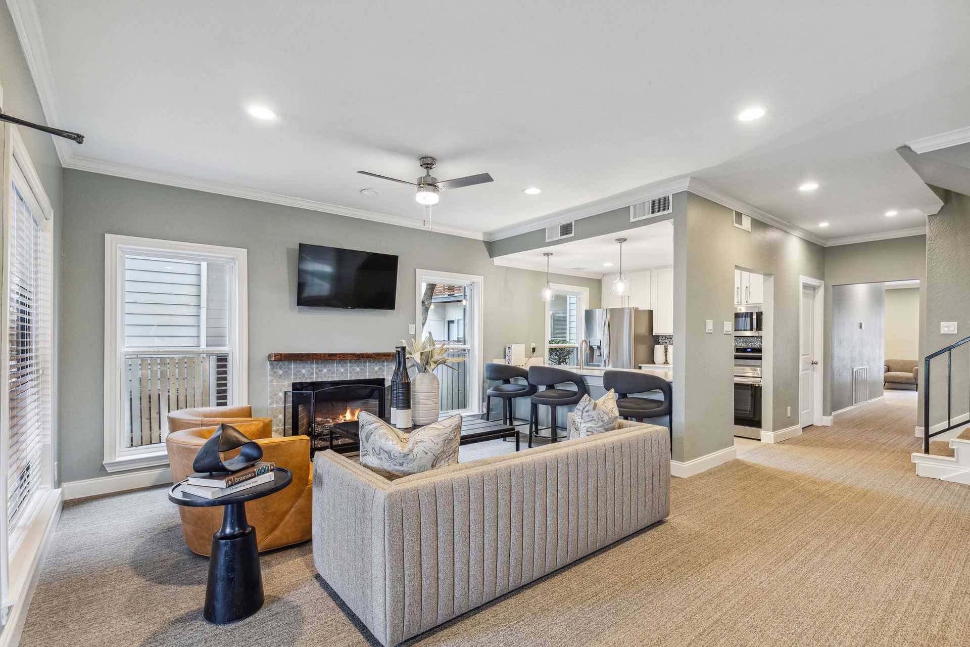Living room with fireplace, sofa, and open kitchen; neutral colors, modern style.