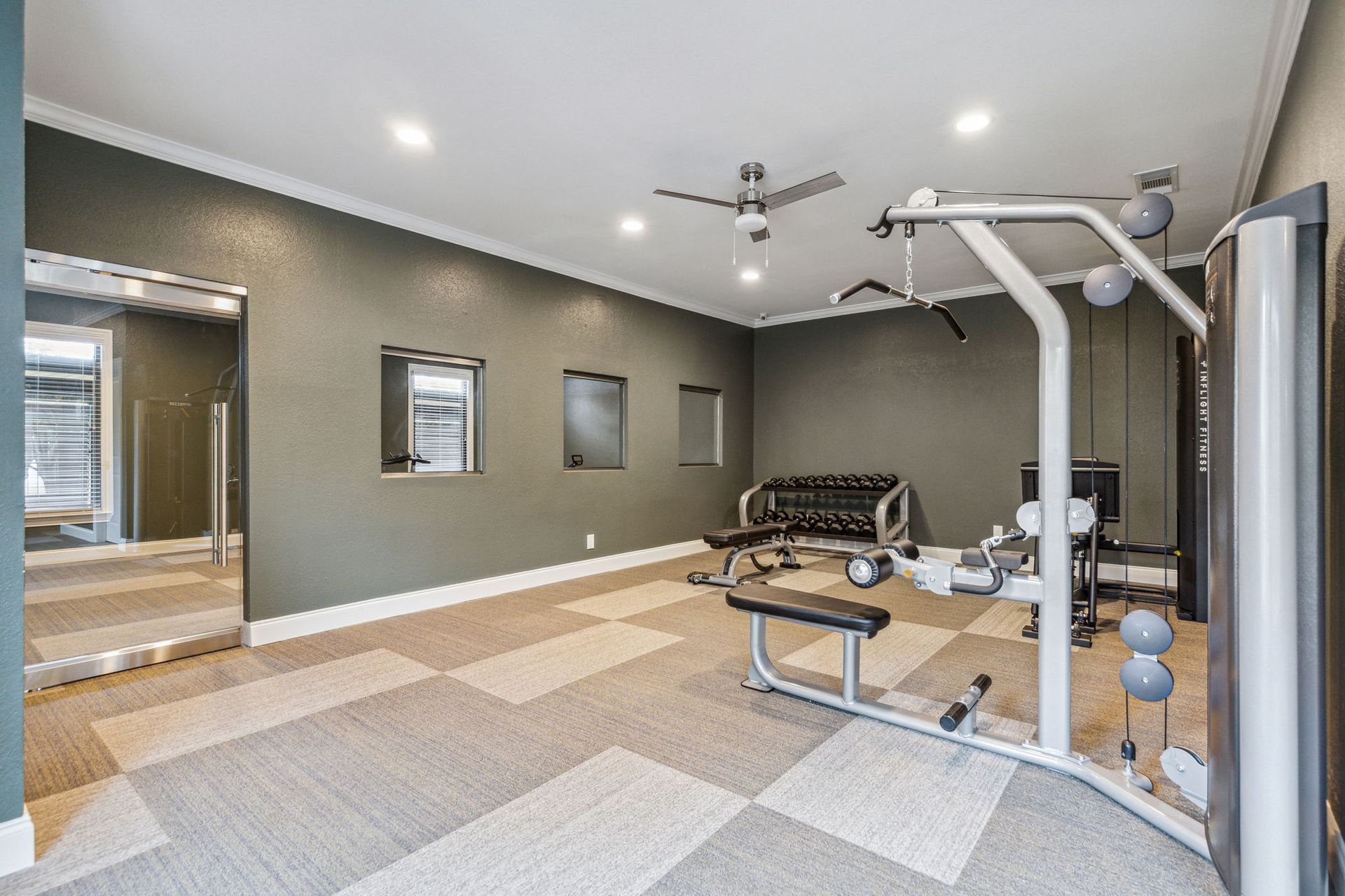 Gym with workout equipment, weights, and checkered floor.