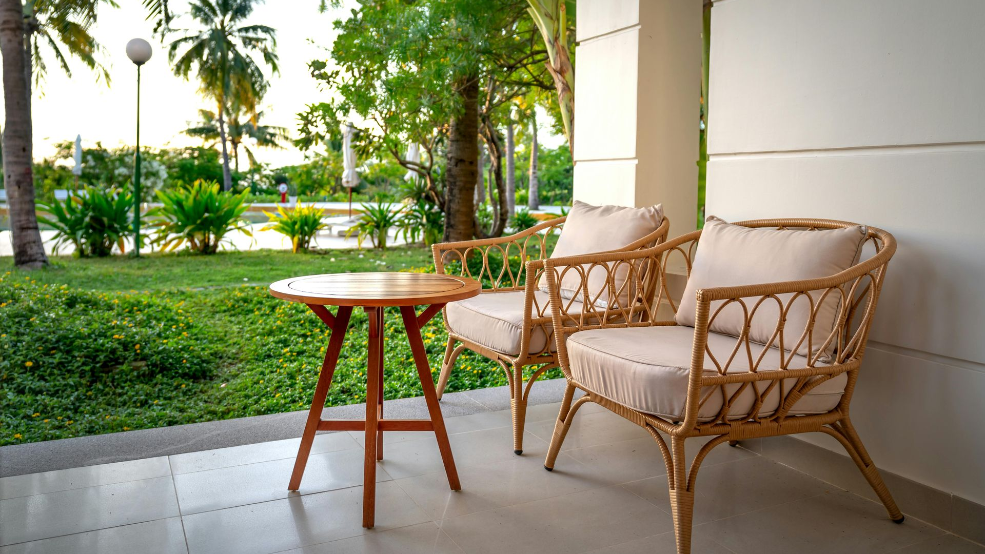Patio with wicker chairs and a small table overlooking a lush tropical garden