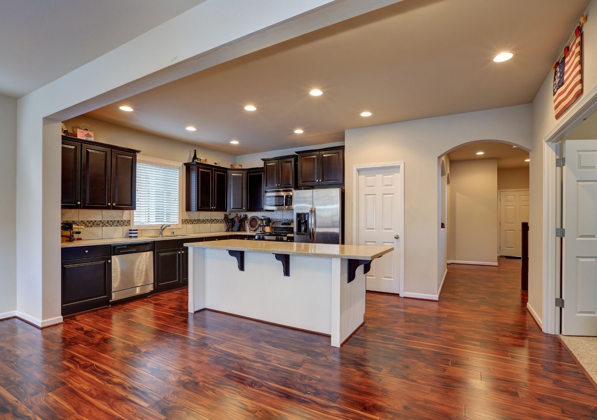 Modern kitchen with light blue cabinets, white countertops, patterned backsplash, stainless steel range, and a black accent wall.