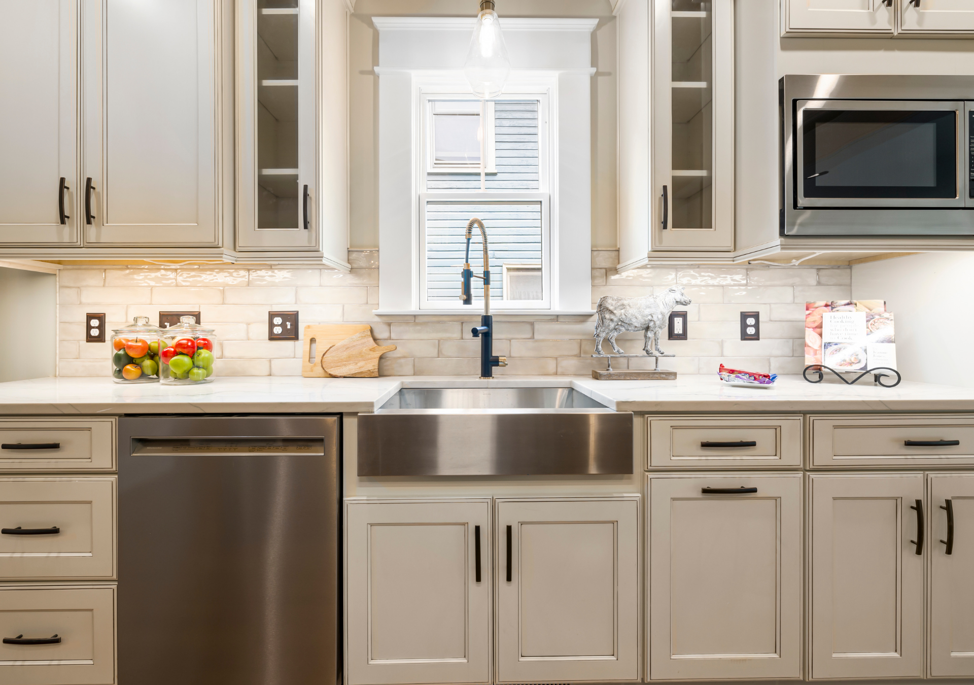 Kitchen with stainless steel sink, appliances, and white cabinets; a window above the sink provides natural light.