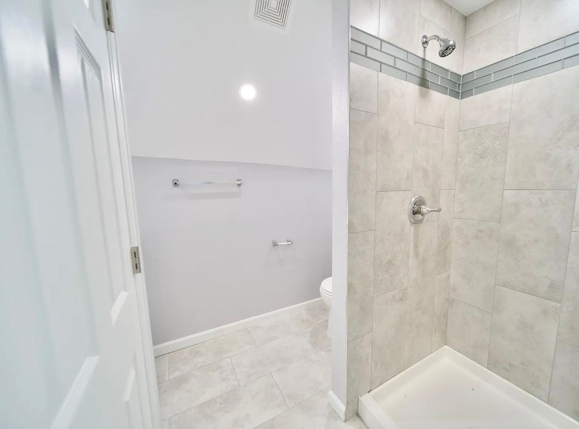 Overhead view of a house roof partially replaced. Brown exposed underlayment, gray shingles, and workers are visible.