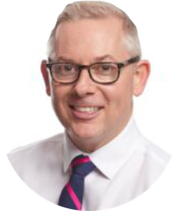 a man wearing glasses and a tie is smiling for the camera .