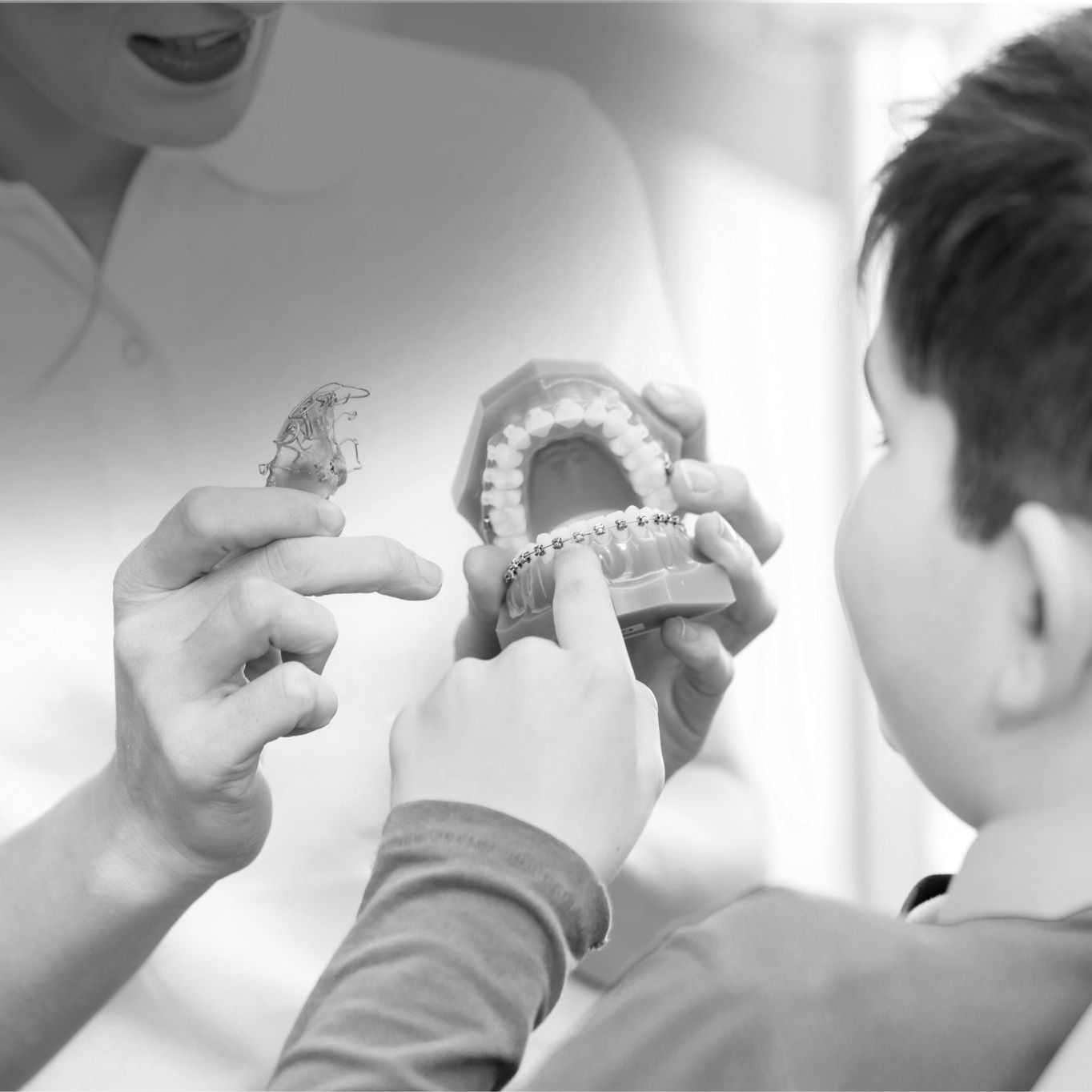 a female orthodontist showing a boy how braces will fit on a model of teeth