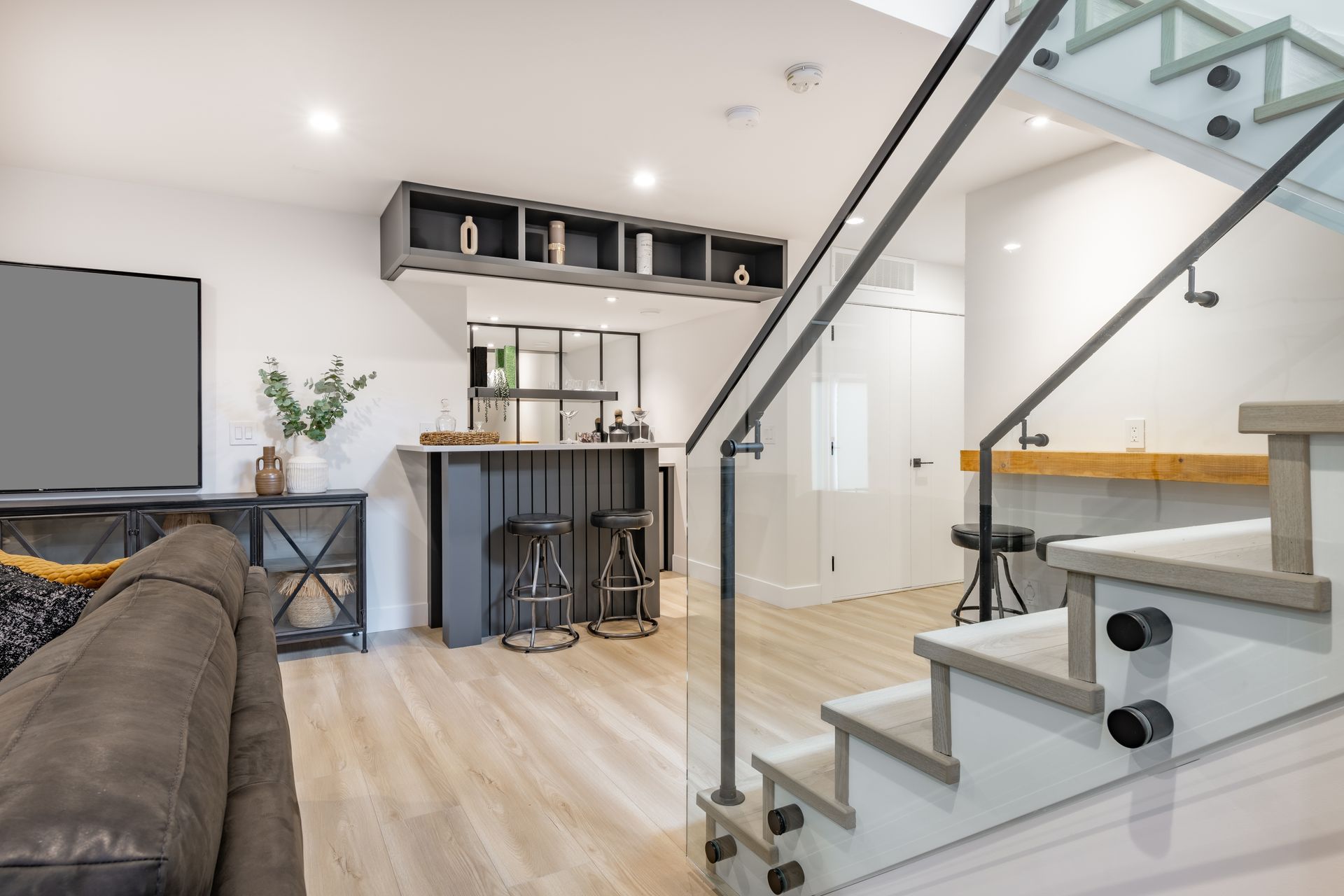 A basement room with a couch and stairs leading up to the second floor.