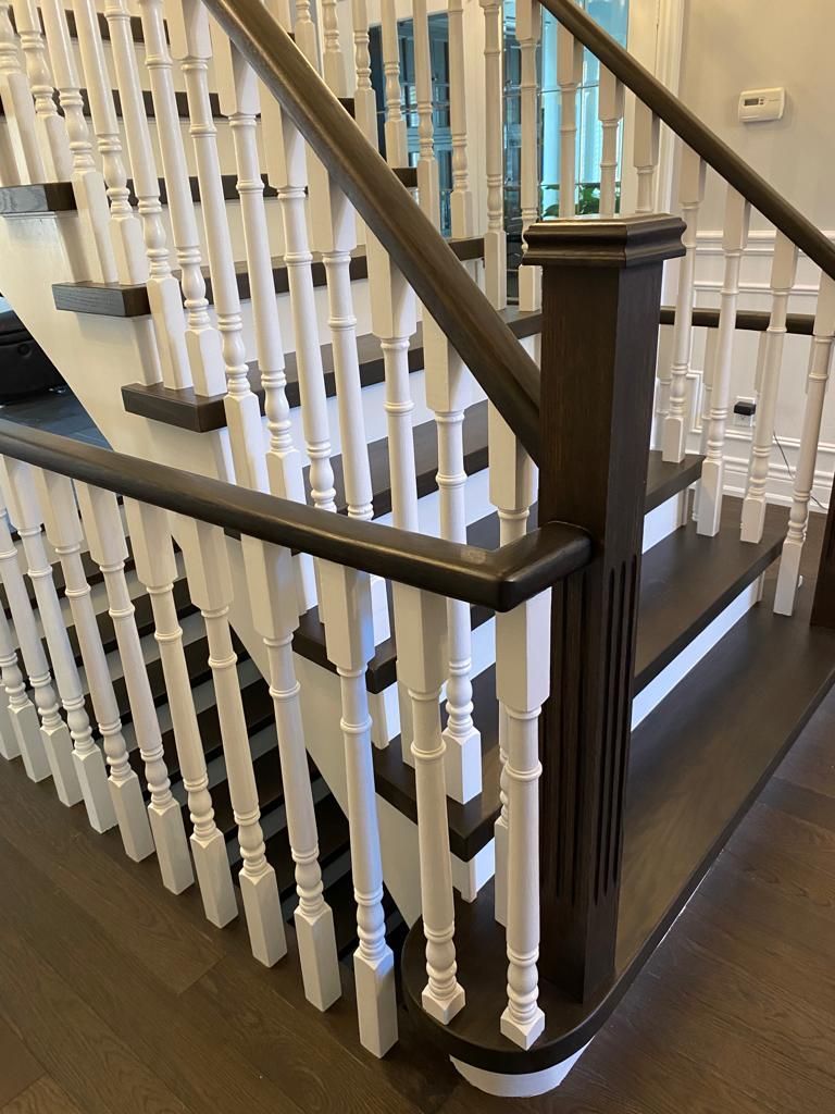 Wooden staircase with dark brown treads and handrails, white balusters.