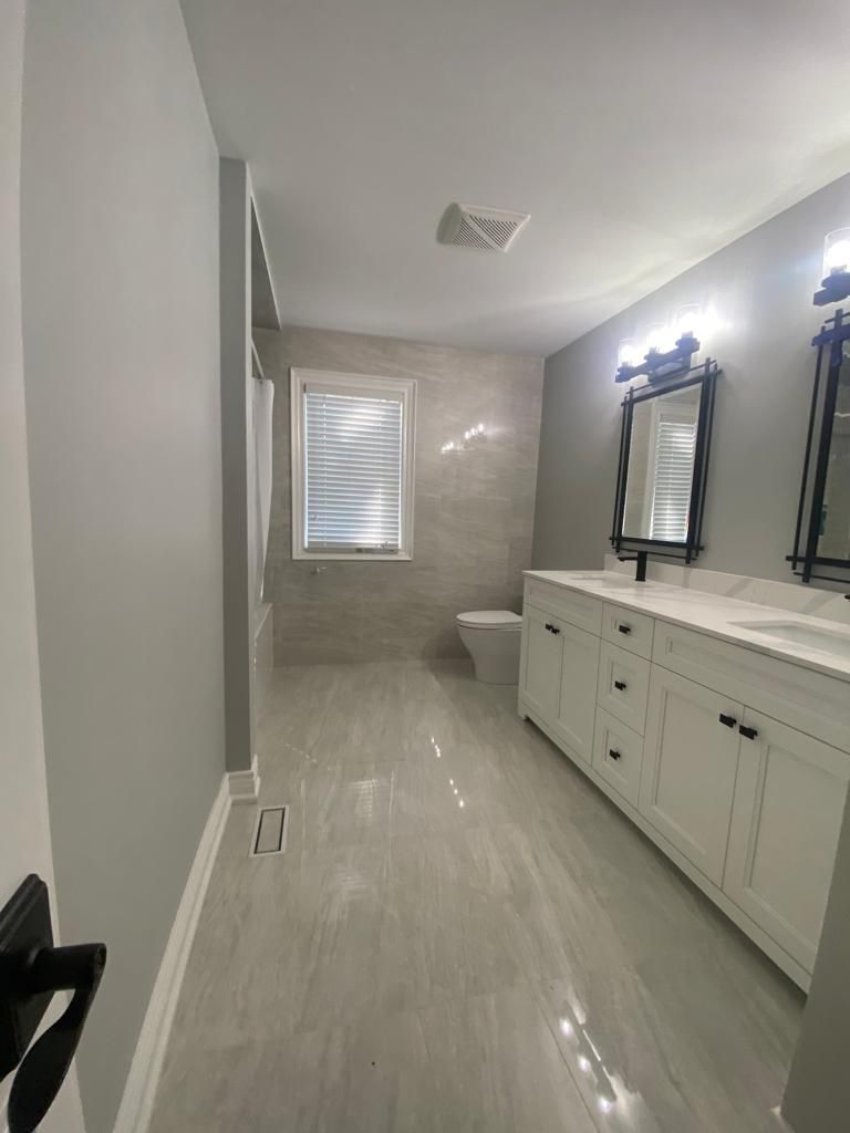 Modern bathroom with gray walls, white vanity, and light gray tile flooring.