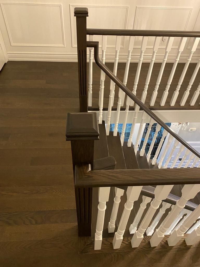 Wooden staircase with dark brown handrails and white spindles.