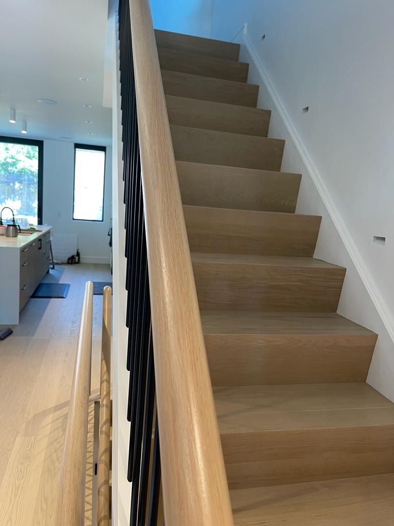 Wooden staircase with black metal railing in a modern home.