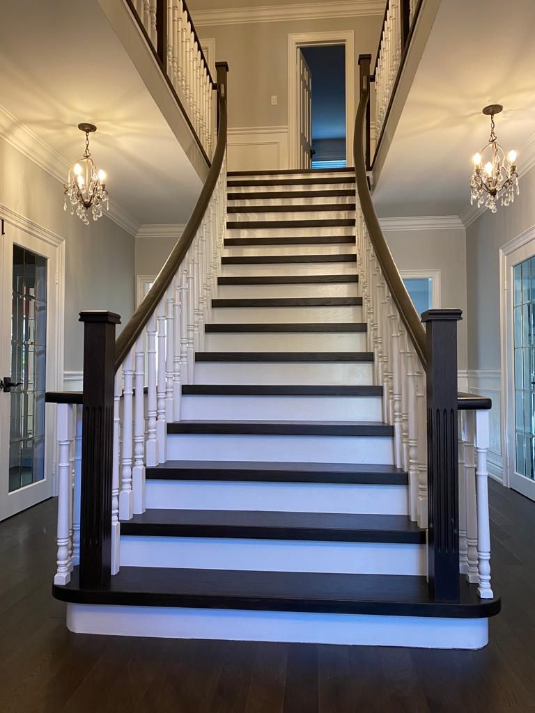Elegant staircase in a home with dark steps and white risers, framed by dark wooden banisters and white railings.