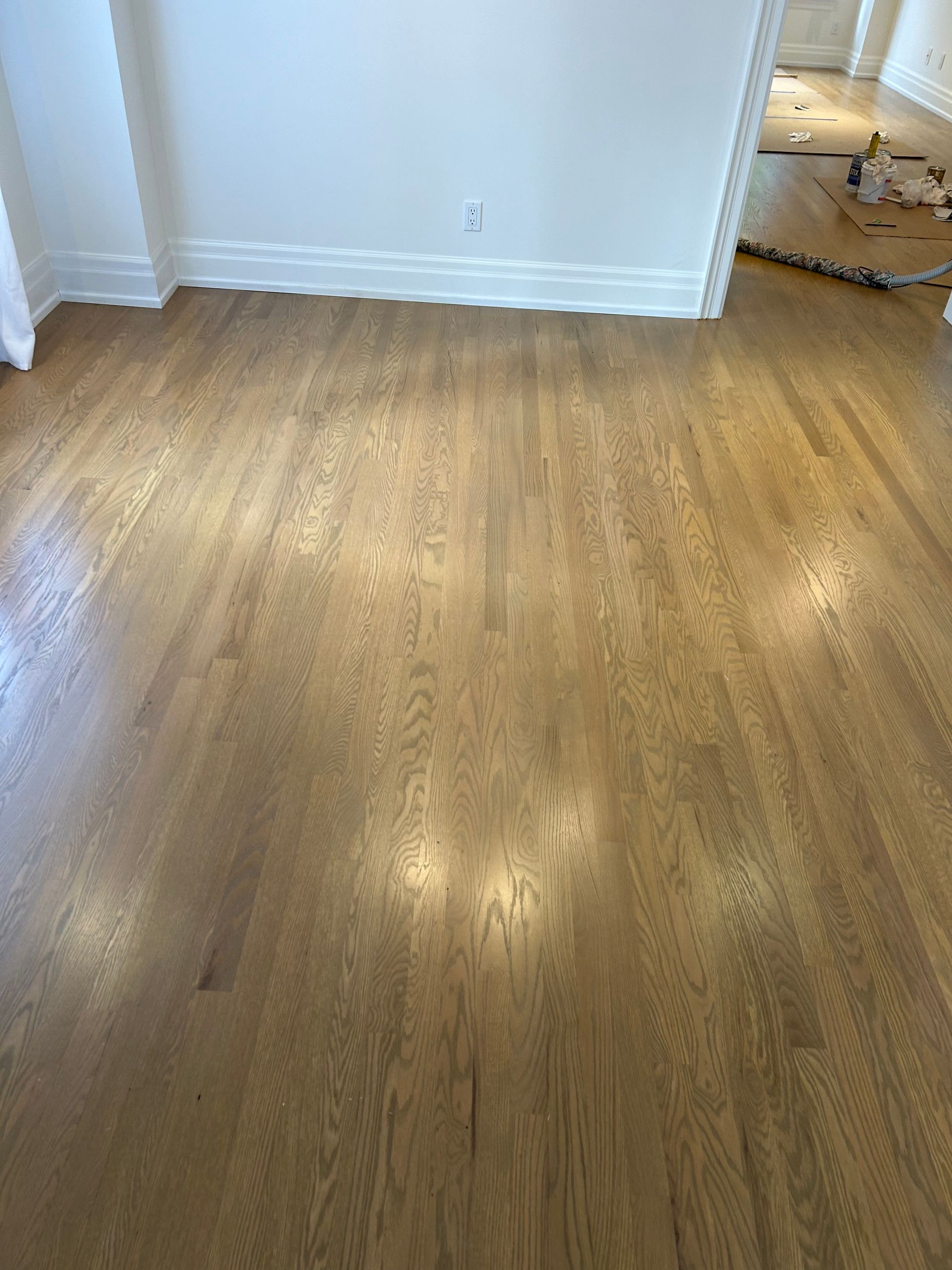 Hardwood floor in a room, with white baseboards and walls.