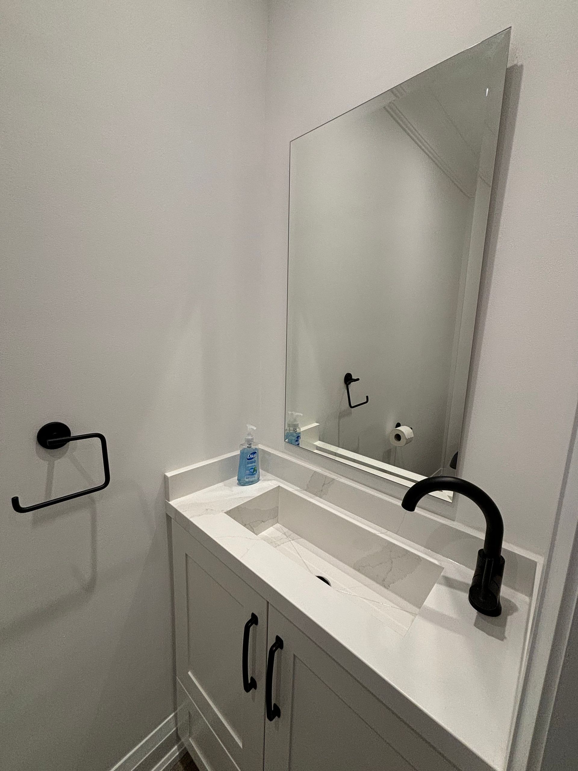 A small bathroom with a white vanity, black faucet, and large mirror.