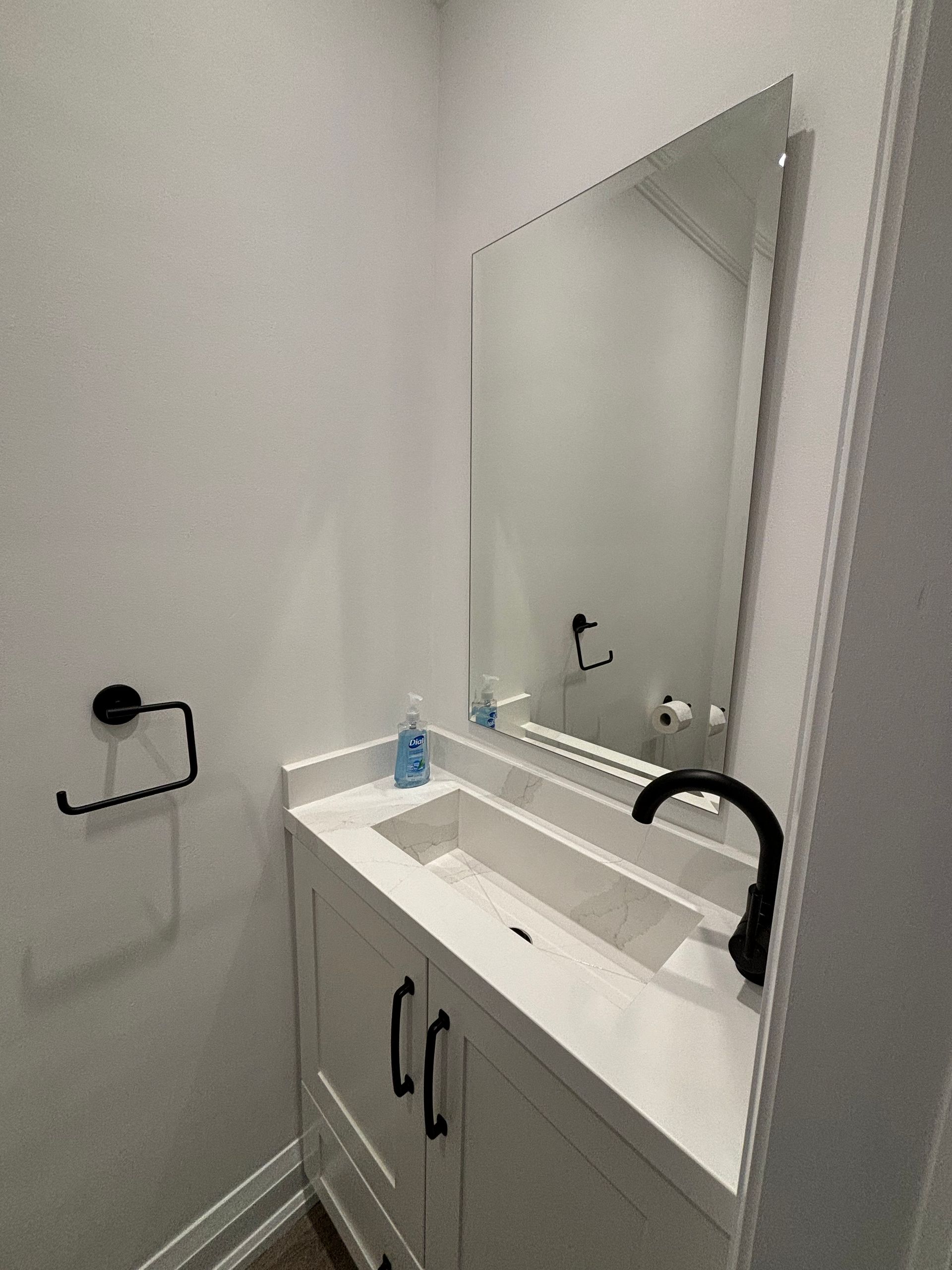 A small white bathroom with a sink, mirror, and black fixtures.