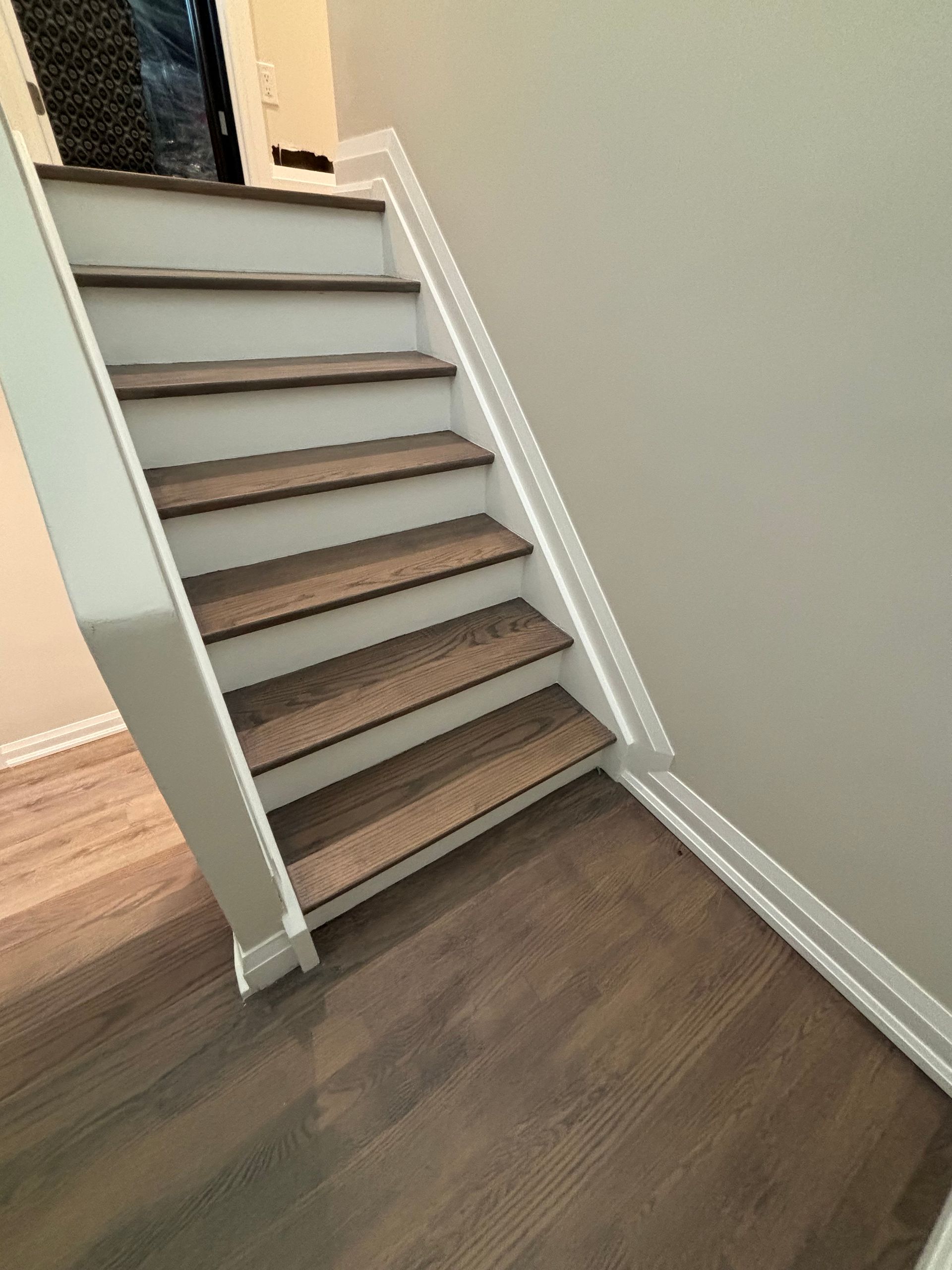 Wooden stairs with white trim and a neutral-colored wall.