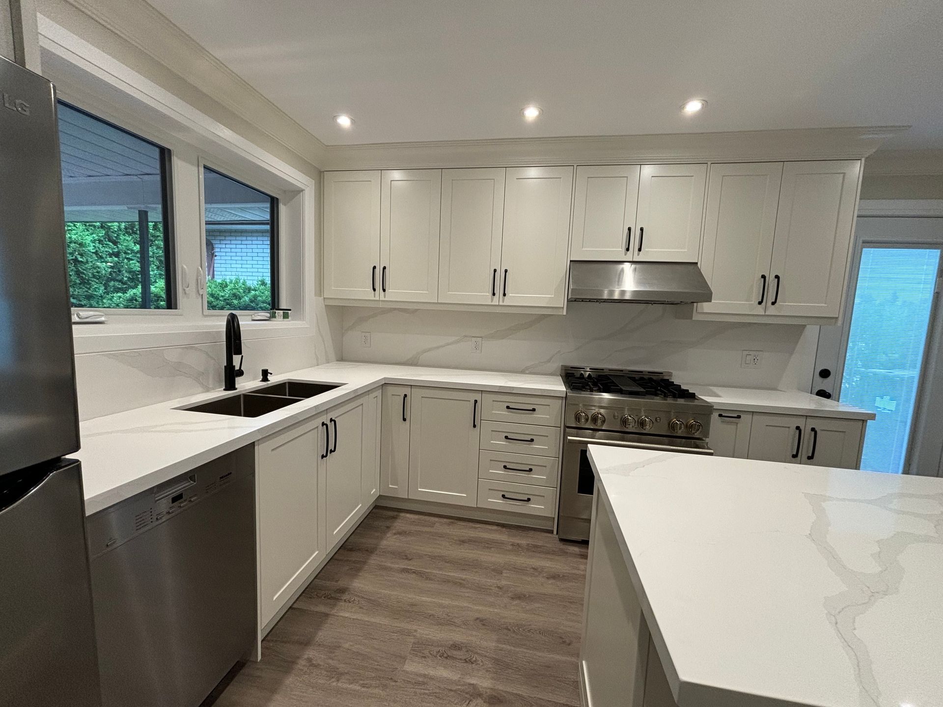 White modern kitchen with stainless steel appliances and countertop.