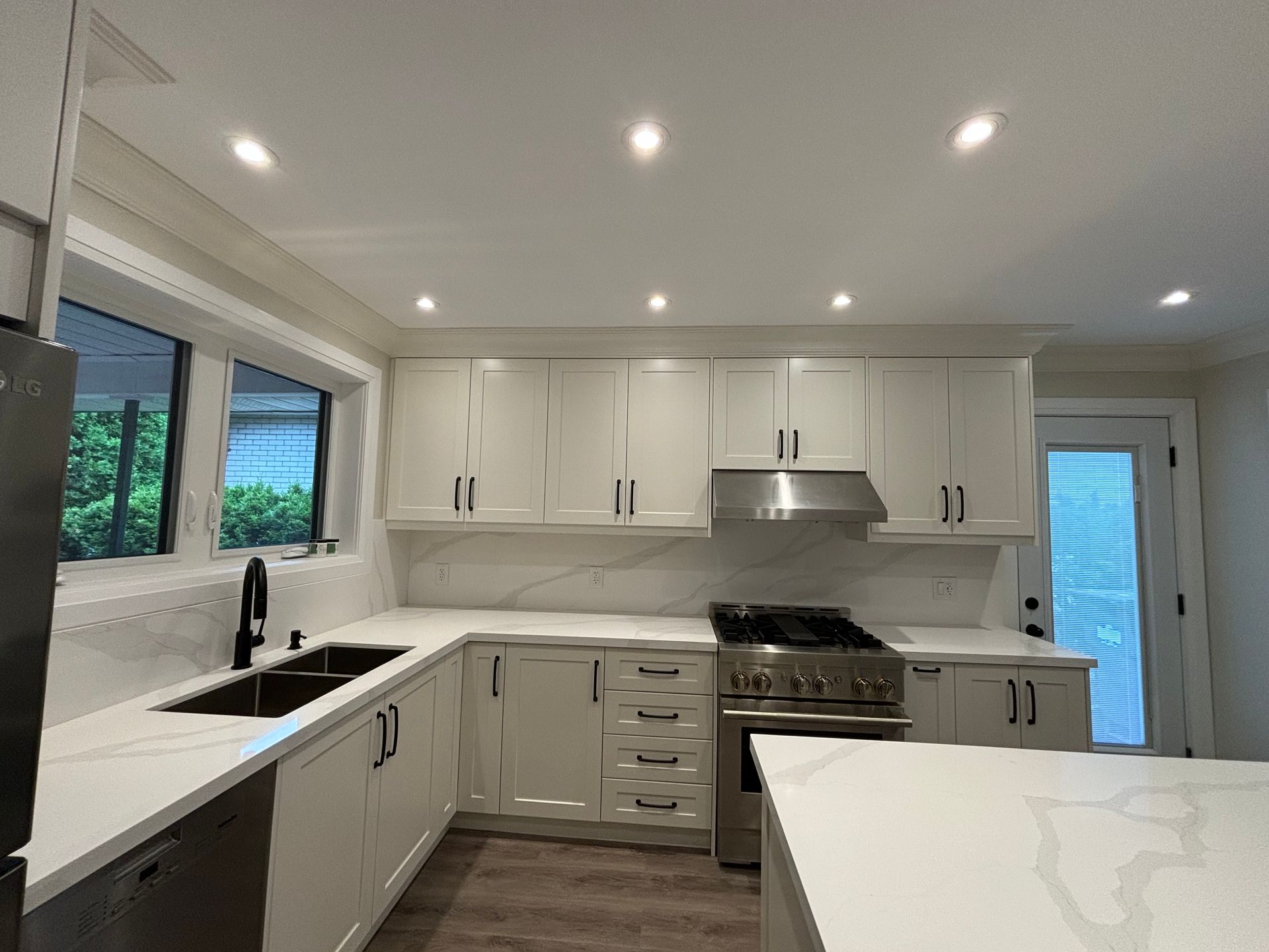 Bright white kitchen with stainless steel appliances, countertops, and cabinets.