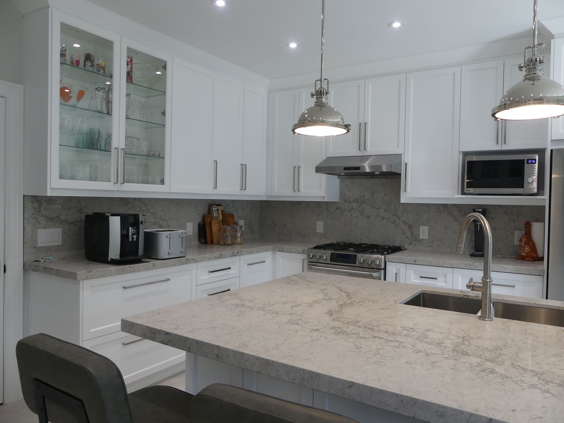 White kitchen with light countertops, stainless steel appliances, and two hanging lights.