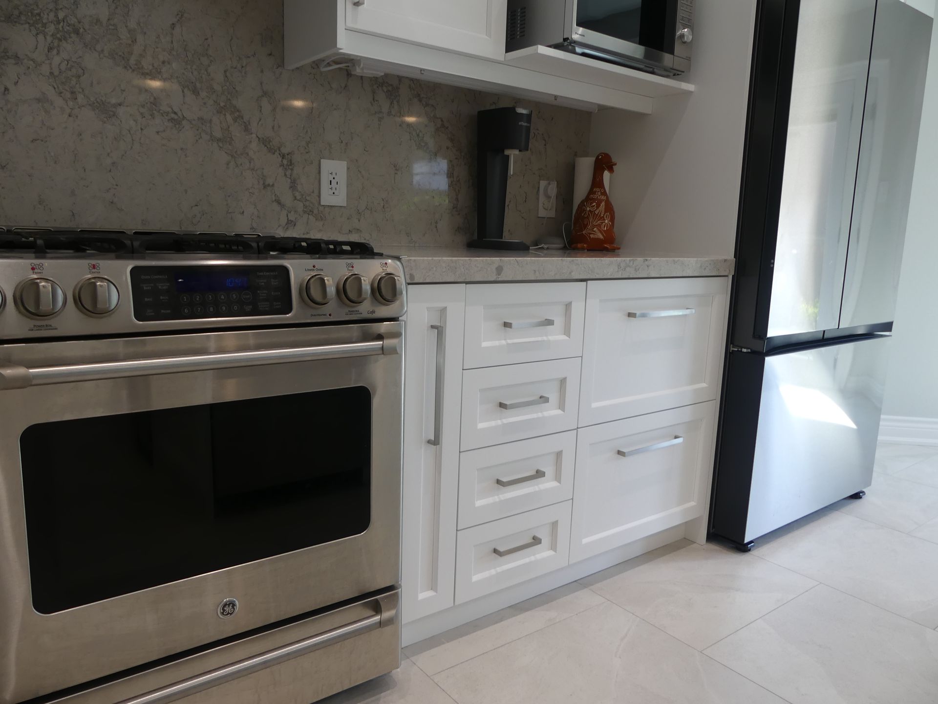 Stainless steel oven next to white cabinets and a refrigerator in a kitchen.