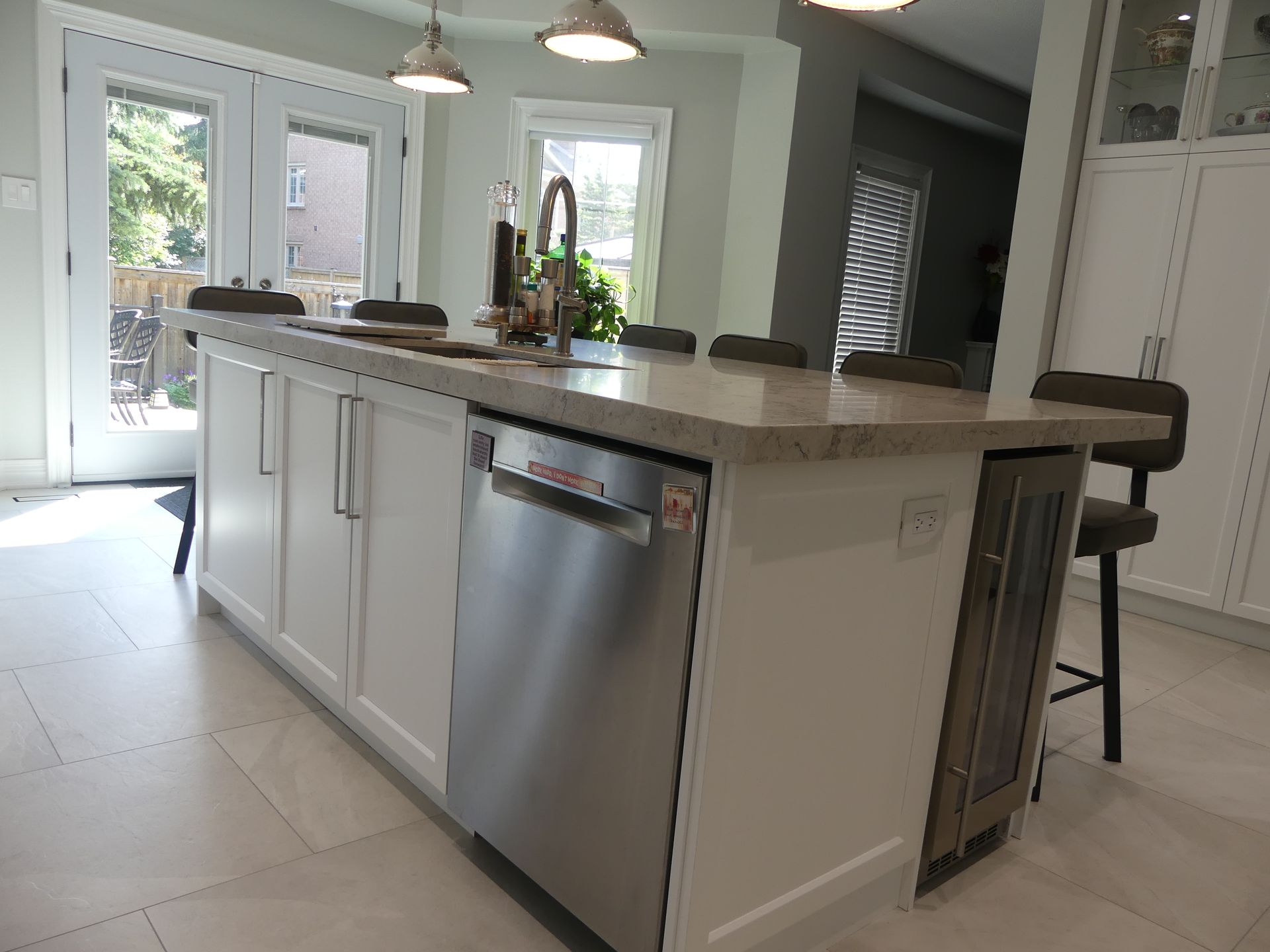 Kitchen island with white cabinets, stainless steel dishwasher, and countertop seating.