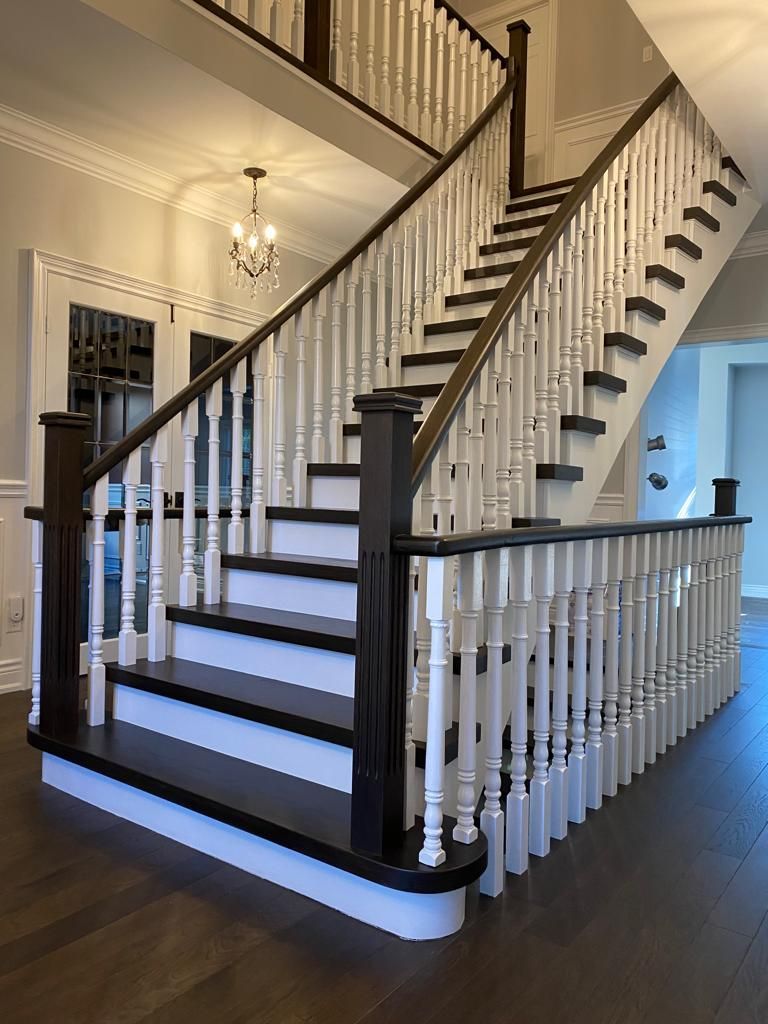 Wooden staircase with dark brown steps, white balusters, and dark brown handrails in a home.