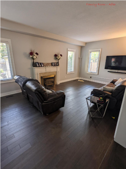 Living room with dark wood floors, fireplace, and two leather recliners. A TV is mounted on the wall.