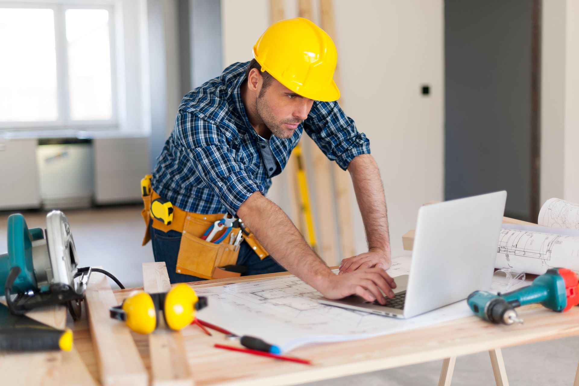 A construction worker is using a laptop computer while sitting at a table.