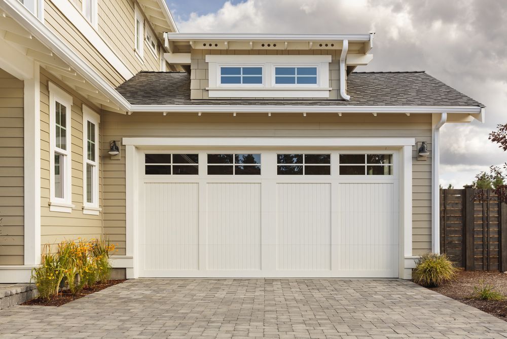 A house with a white garage door and a brick driveway.