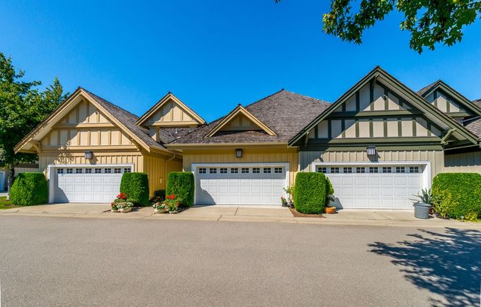 A row of houses with white garage doors on a sunny day.