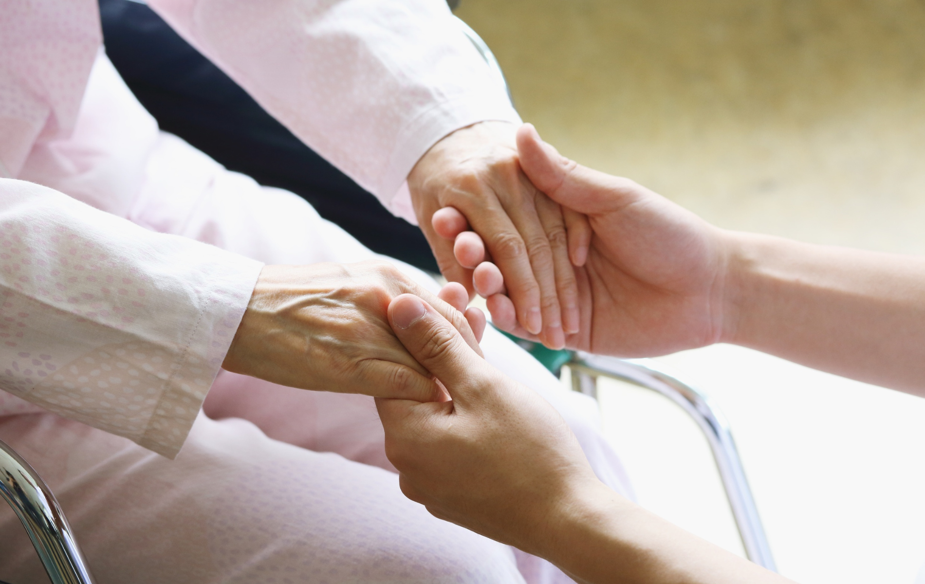 Hands of two people, one older and one younger, clasped together in a comforting gesture.