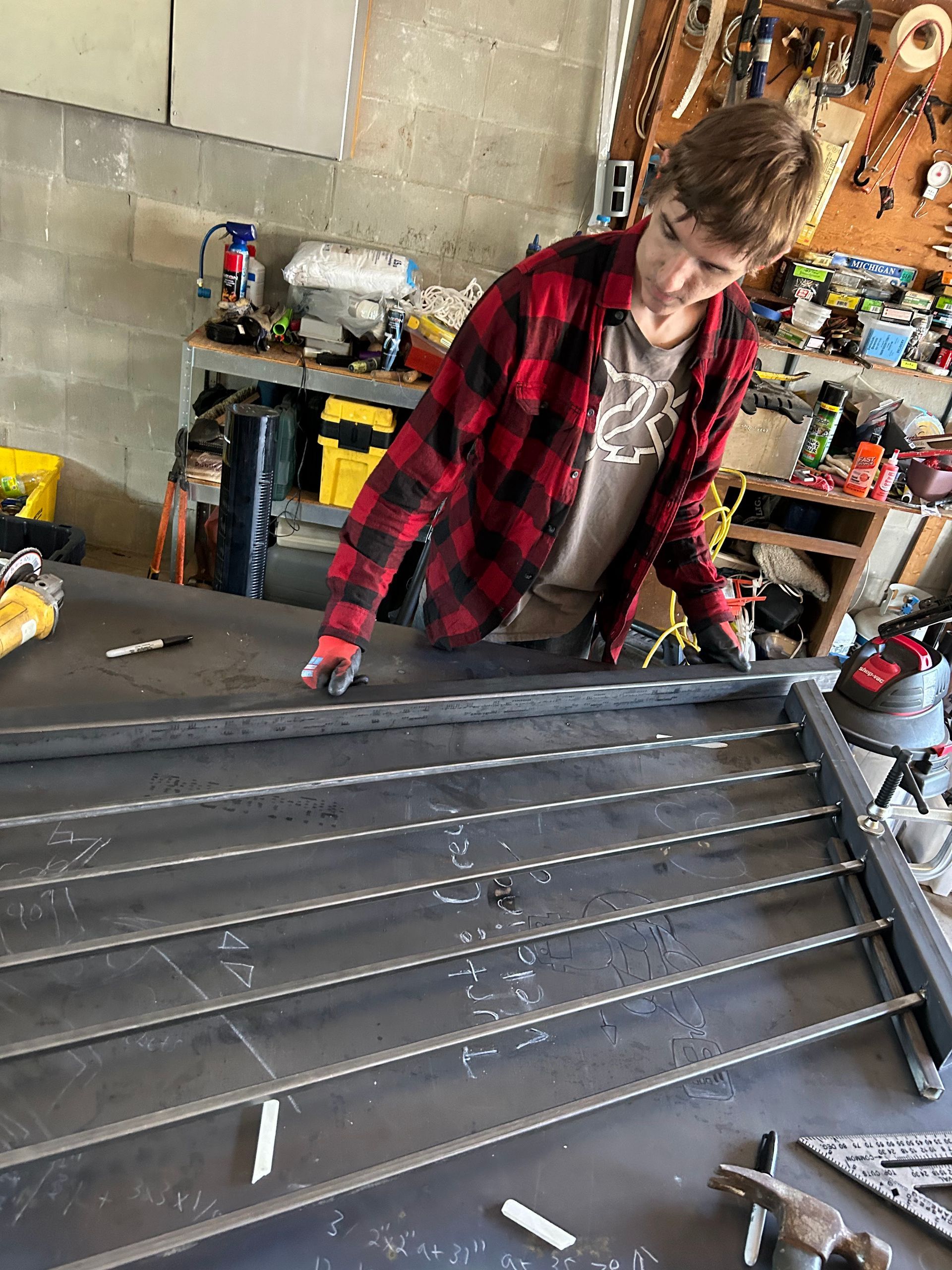 A young boy is working on a piece of metal in a garage.