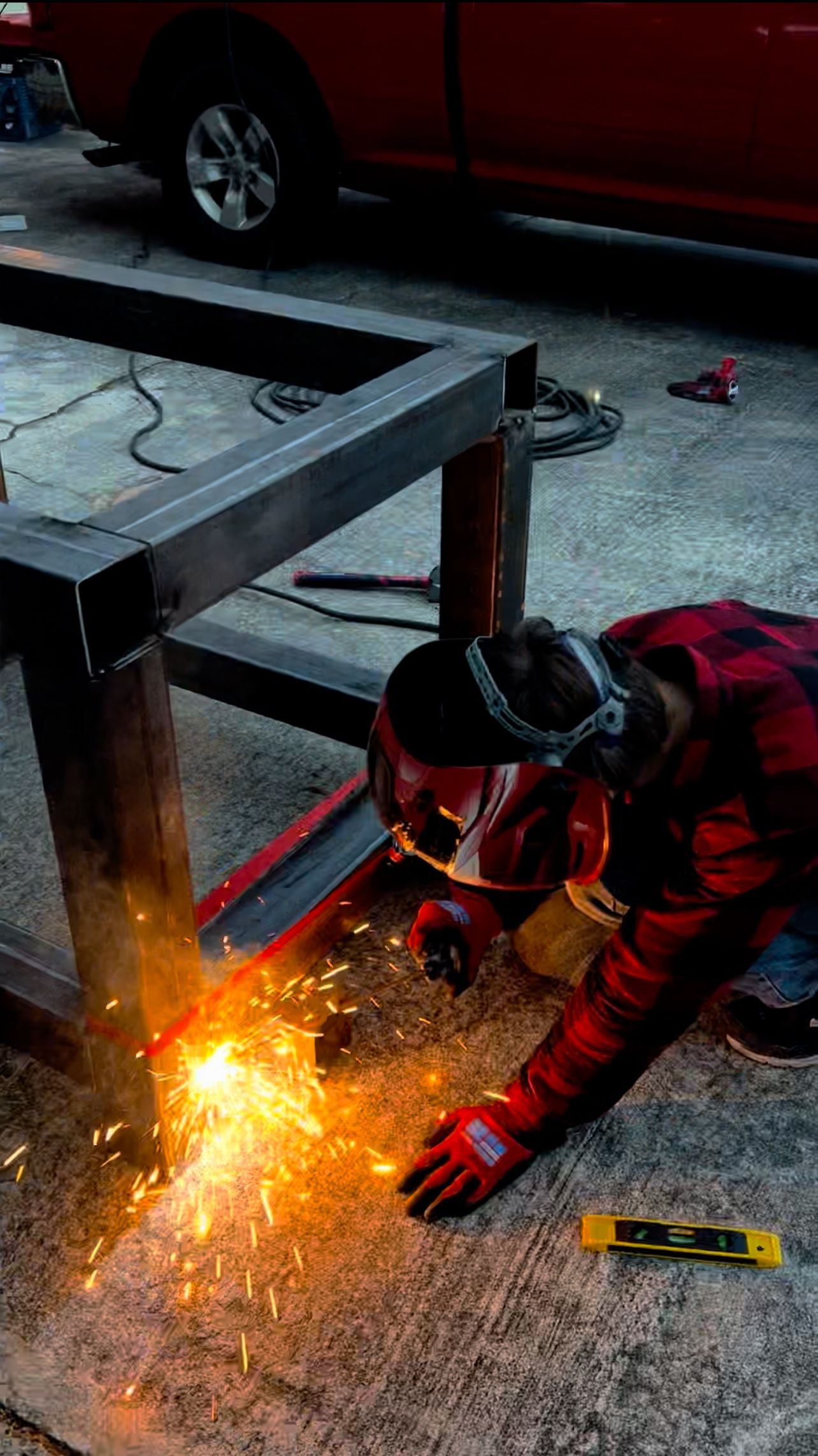 A man is welding a piece of metal in a garage.