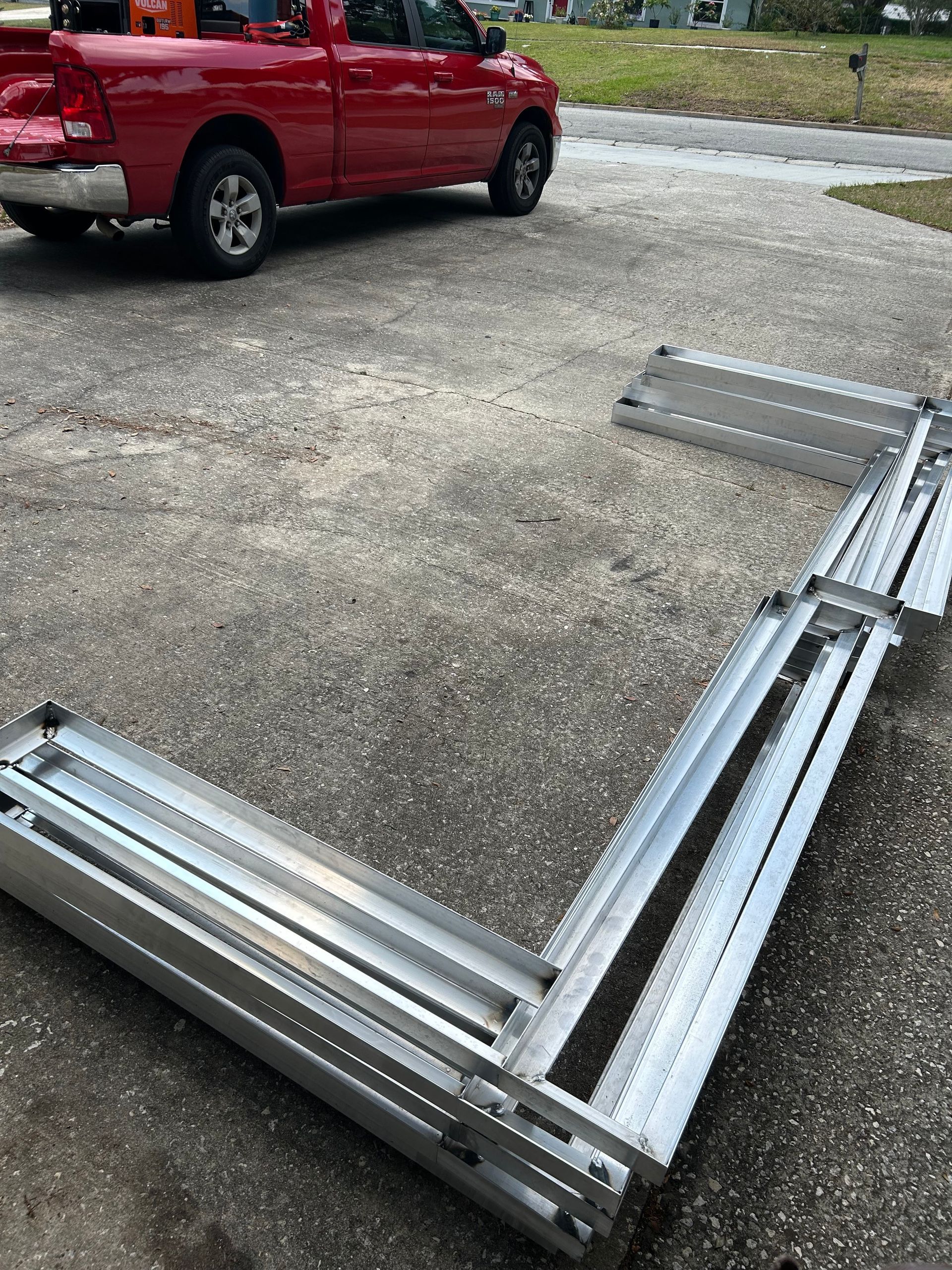 A red truck is parked in a parking lot next to a pile of metal.