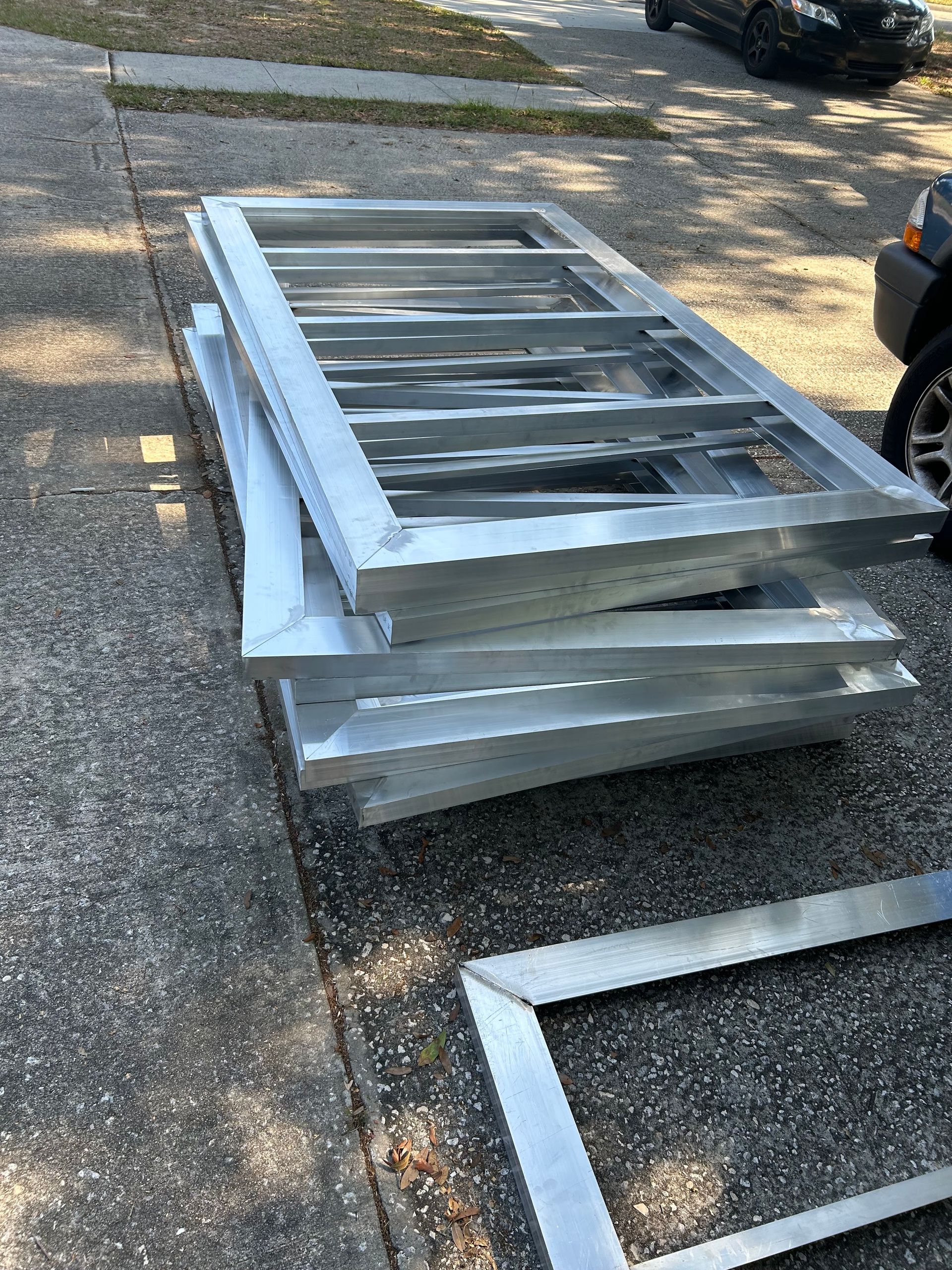 A stack of metal frames sitting on the sidewalk next to a car.