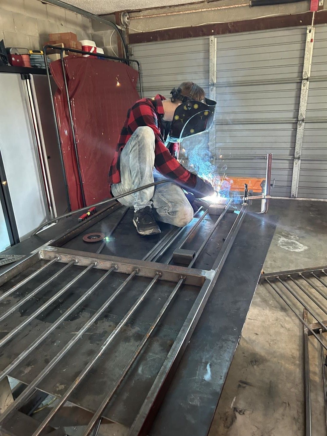 A man is welding a piece of metal in a garage.