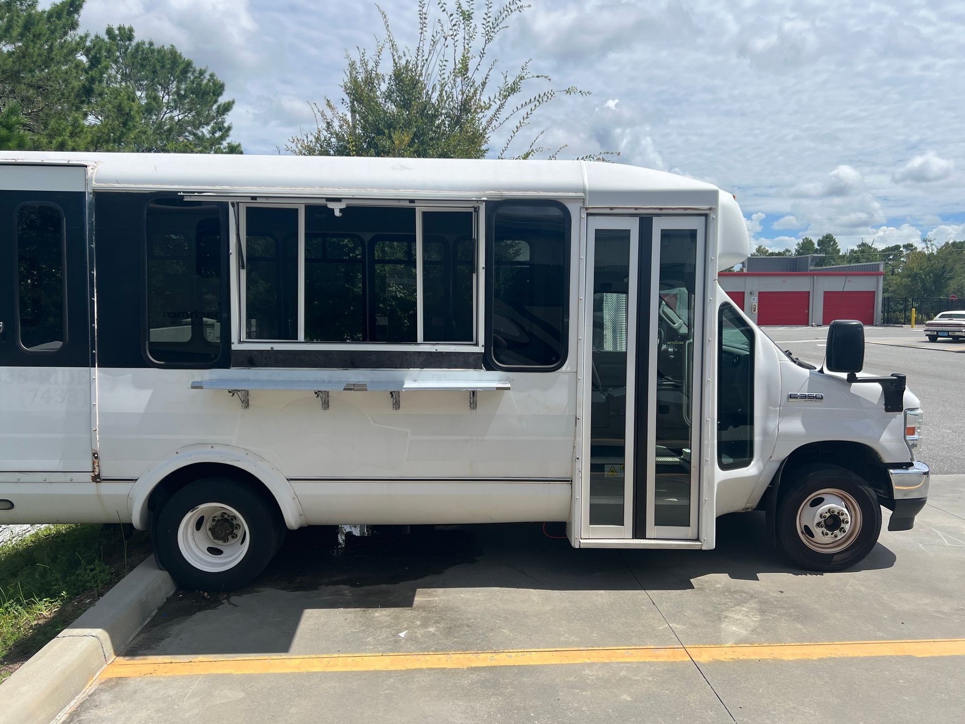 A white bus is parked in a parking lot with the door open.