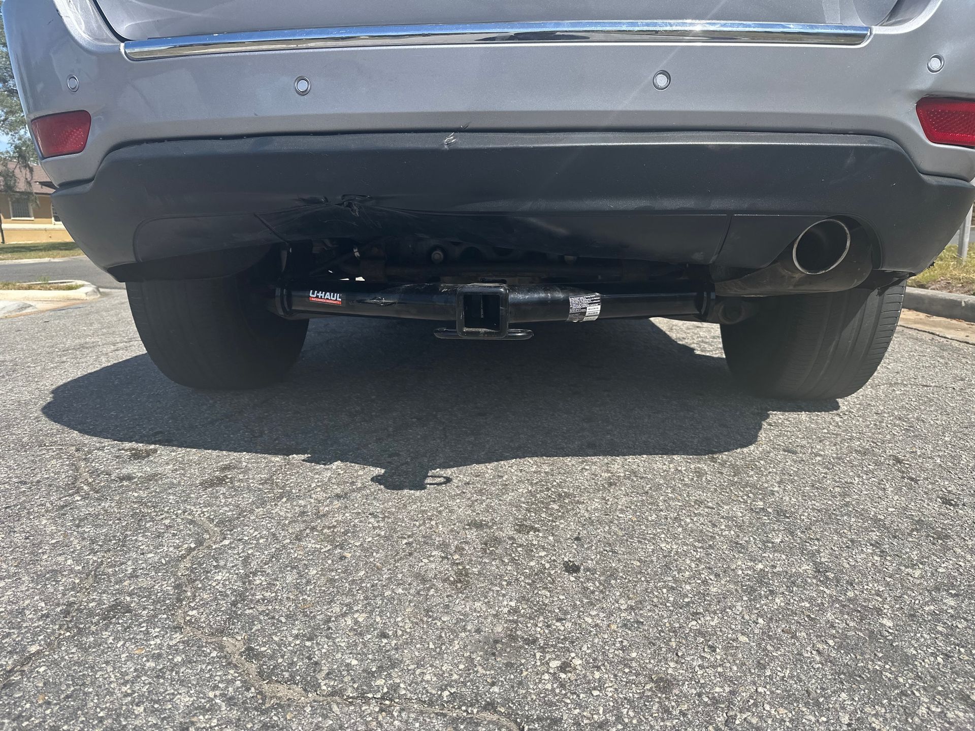 The rear end of a silver car is parked on the side of the road.