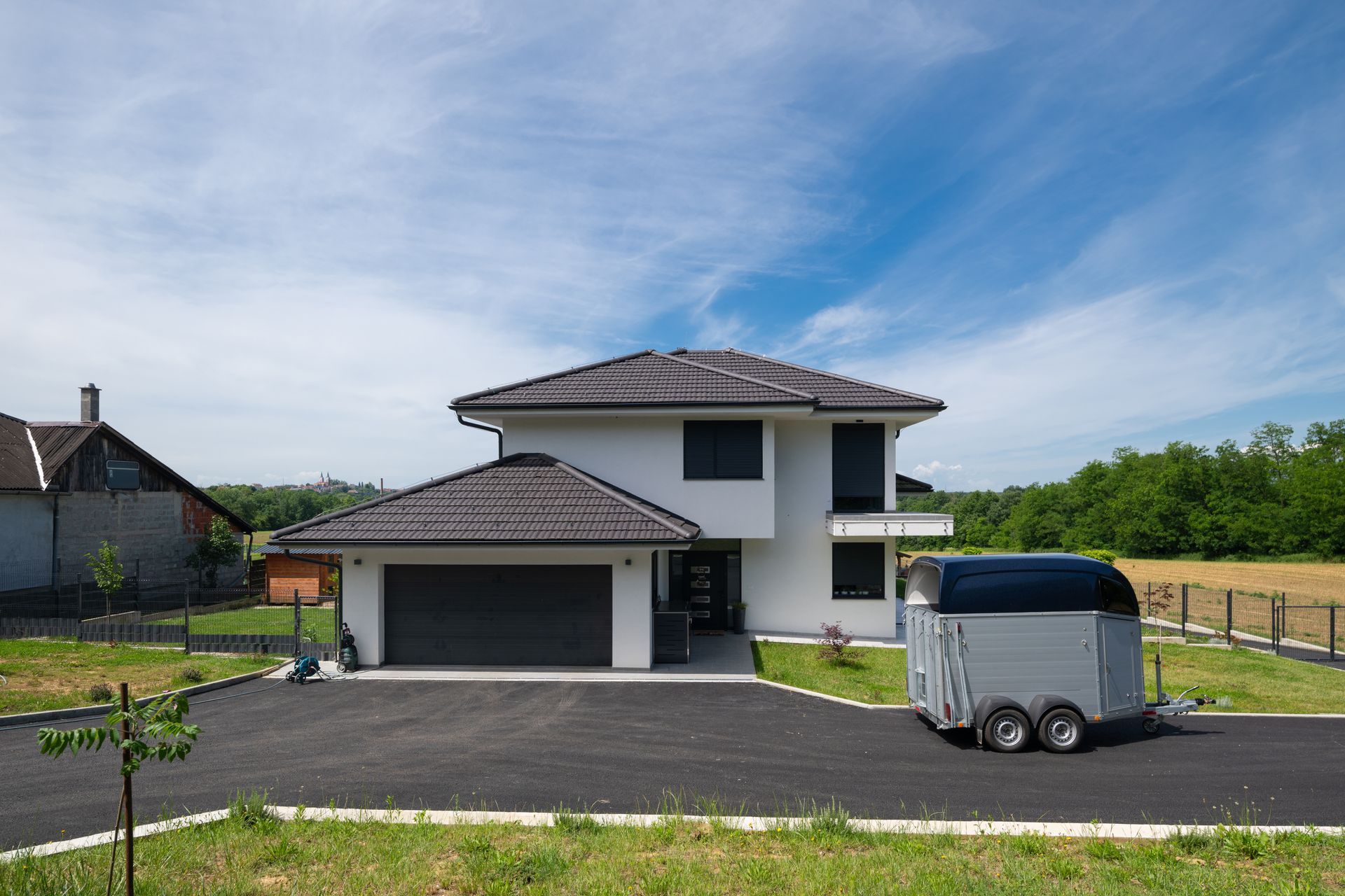 A modern modular house with a garage and a trailer on a paved driveway, after driveway replacement. A modern modular house with a garage and a trailer on a paved driveway, after driveway replacement.