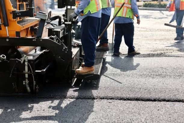 A commercial paving contractor operates a machine, spreading hot asphalt on a road project.