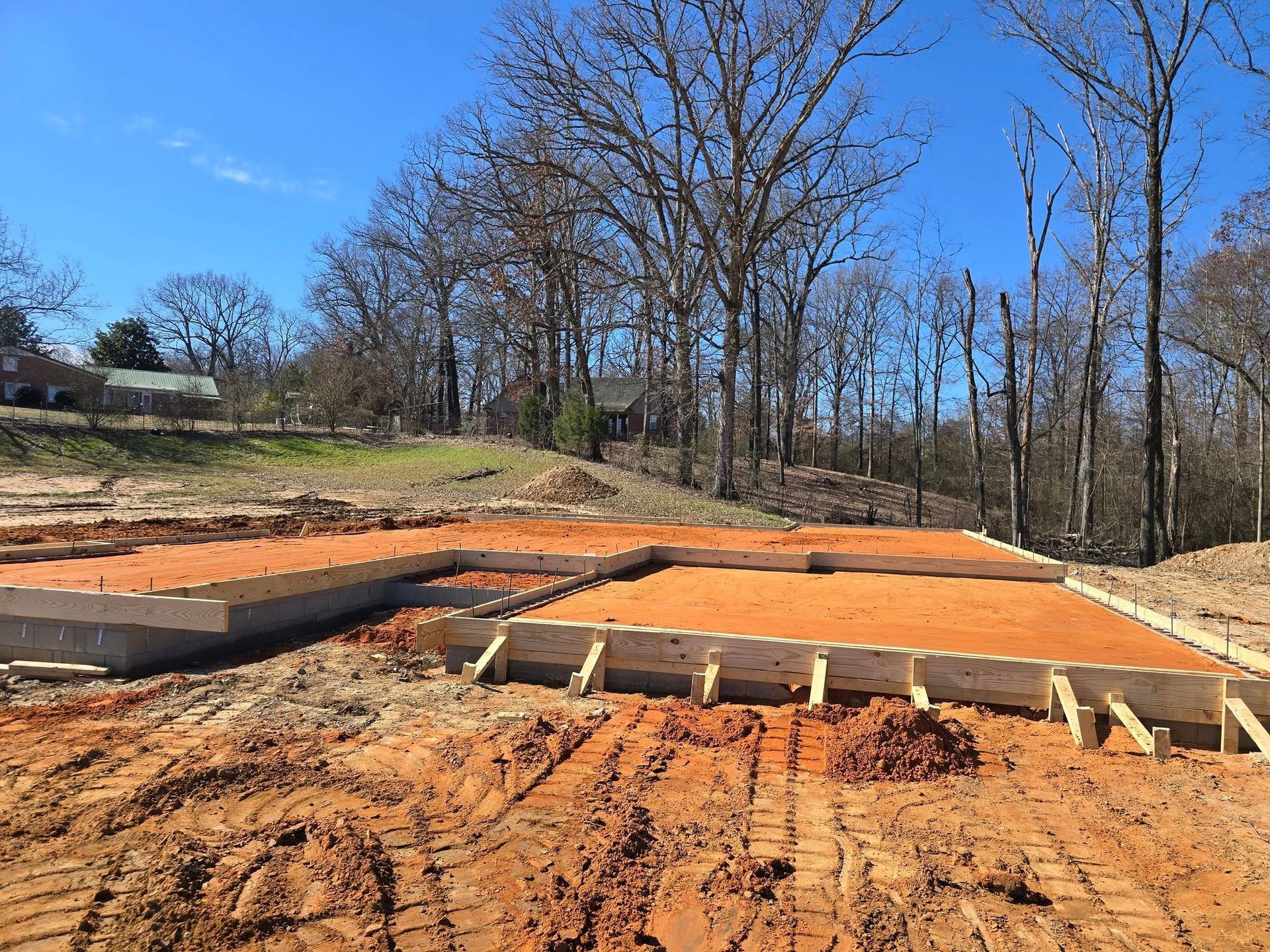 A little boy is holding a rake in front of a tractor.
