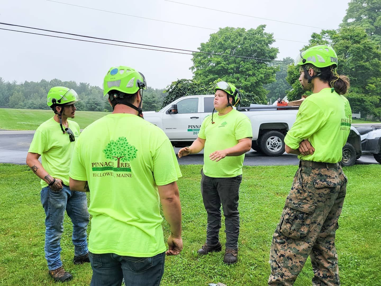 A group of men wearing neon green shirts and helmets are standing in a grassy field.
