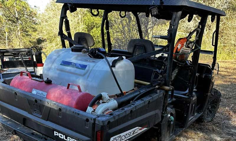 Black Polaris UTV with large tanks and equipment in the back, outdoors.