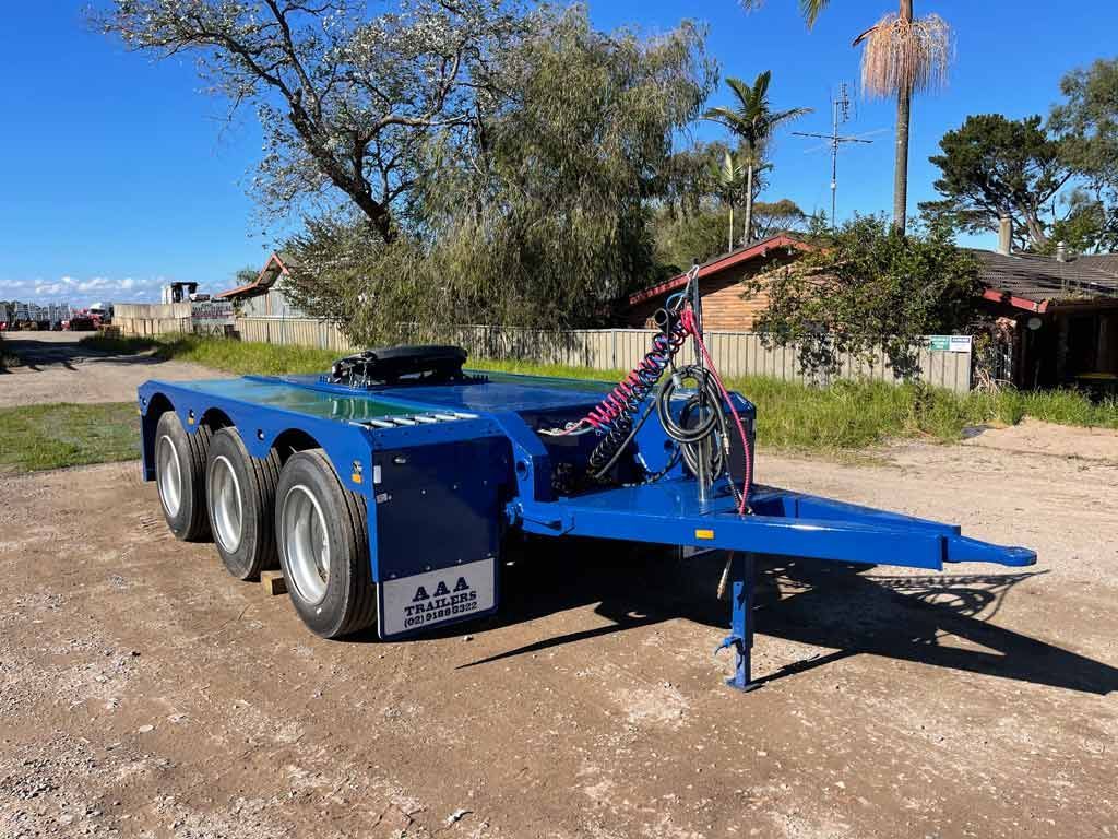 A blue trailer is parked on the side of a dirt road.