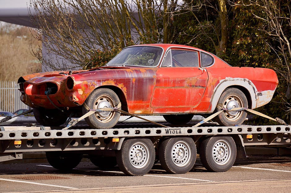 A red car is sitting on top of a trailer