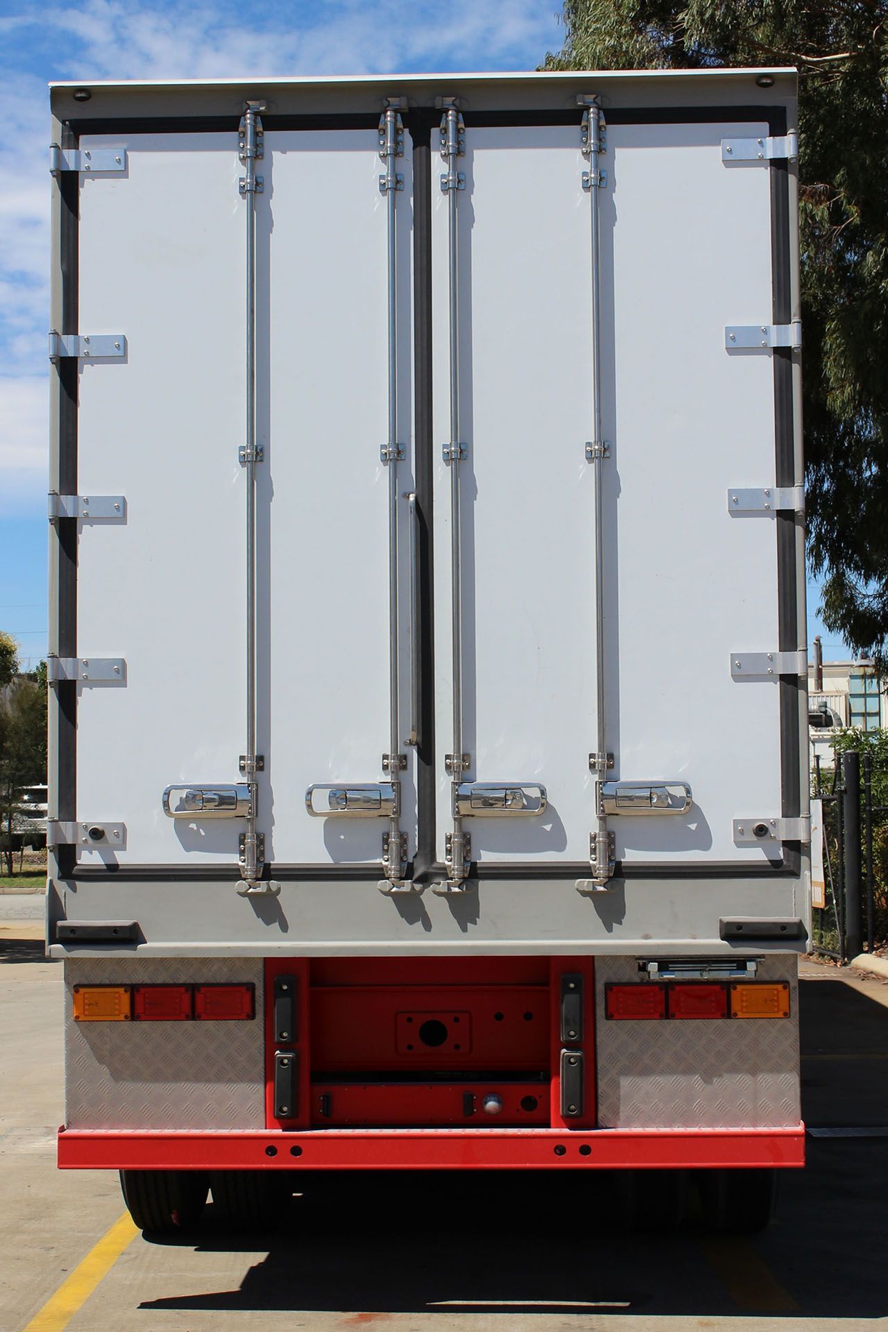 A white truck with red trim is parked in a parking lot